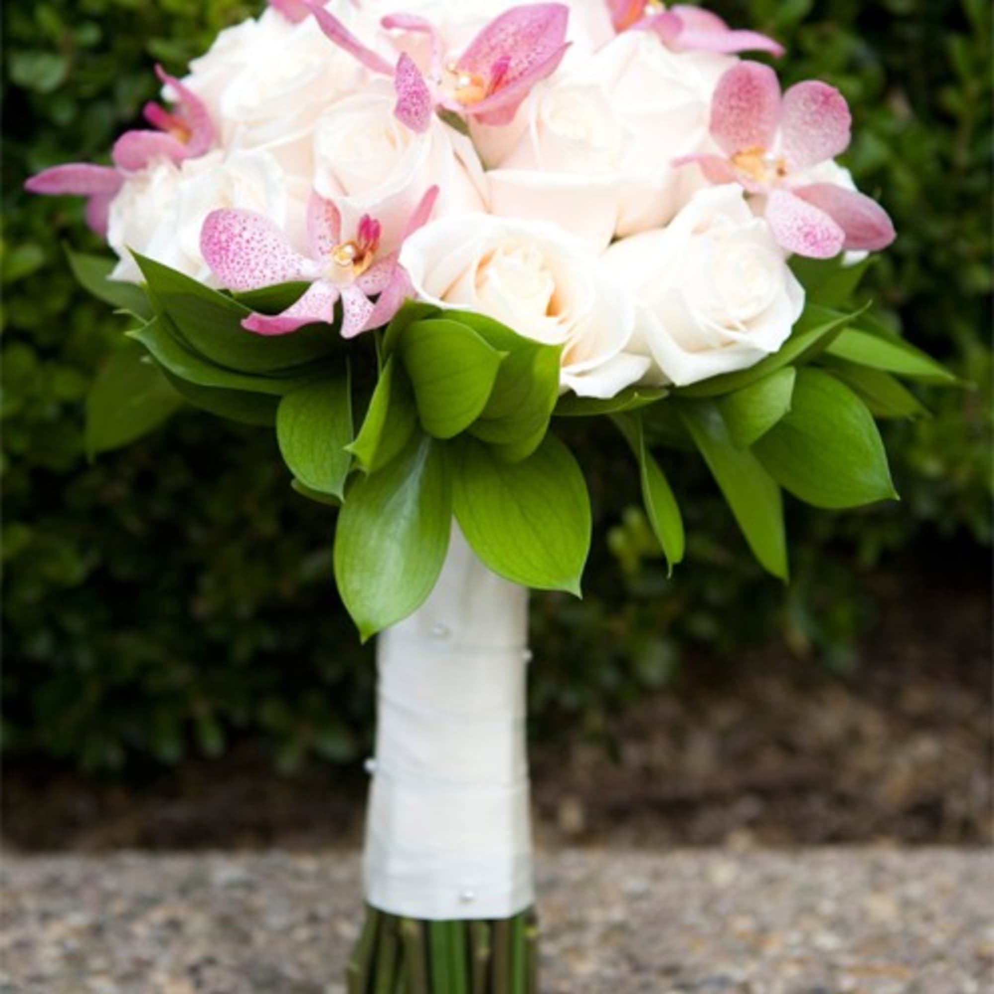 Classic Roses dressed with blooms of exotic Mokara Orchids, make up this