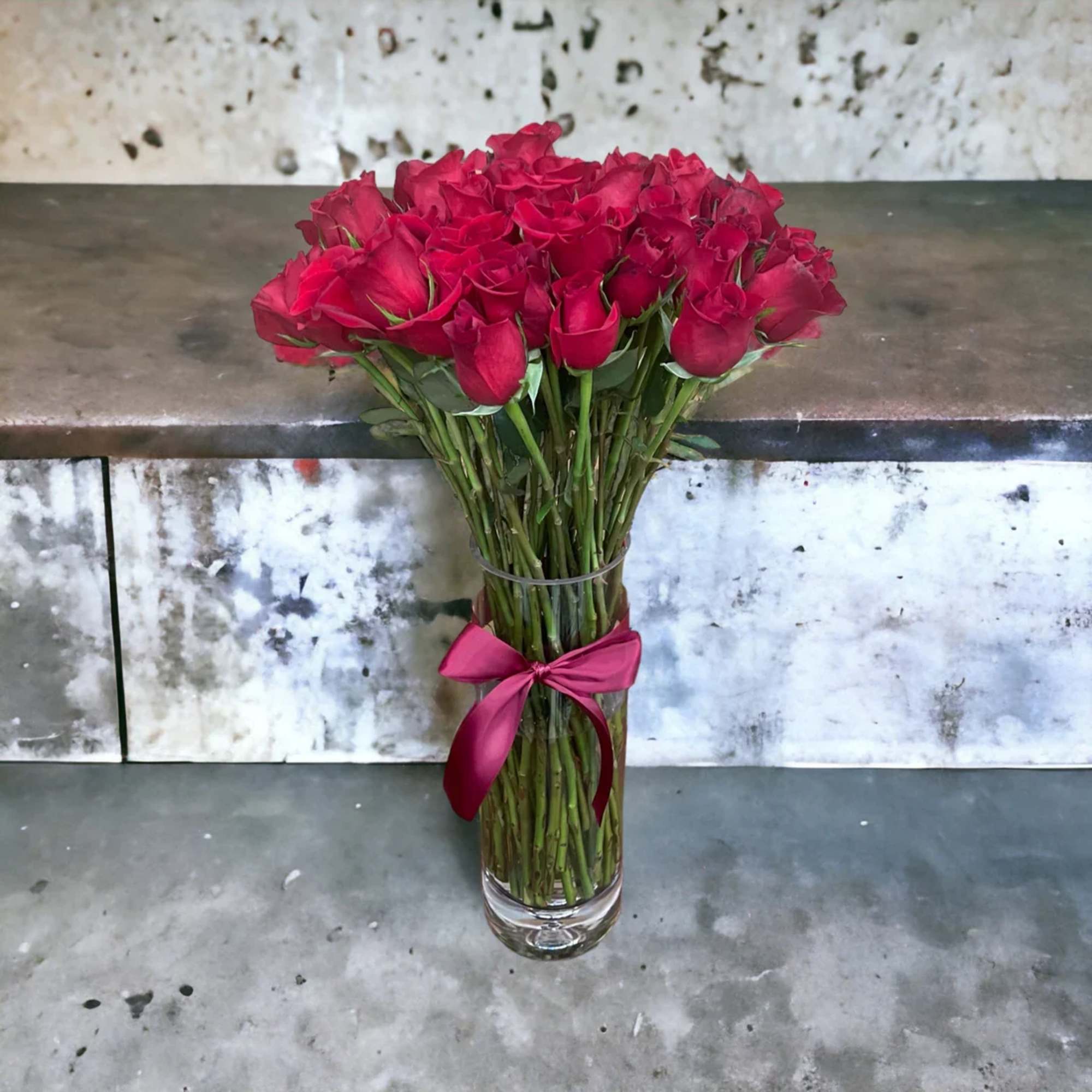 50 stems of red roses in a clear large illusion vase. Picked