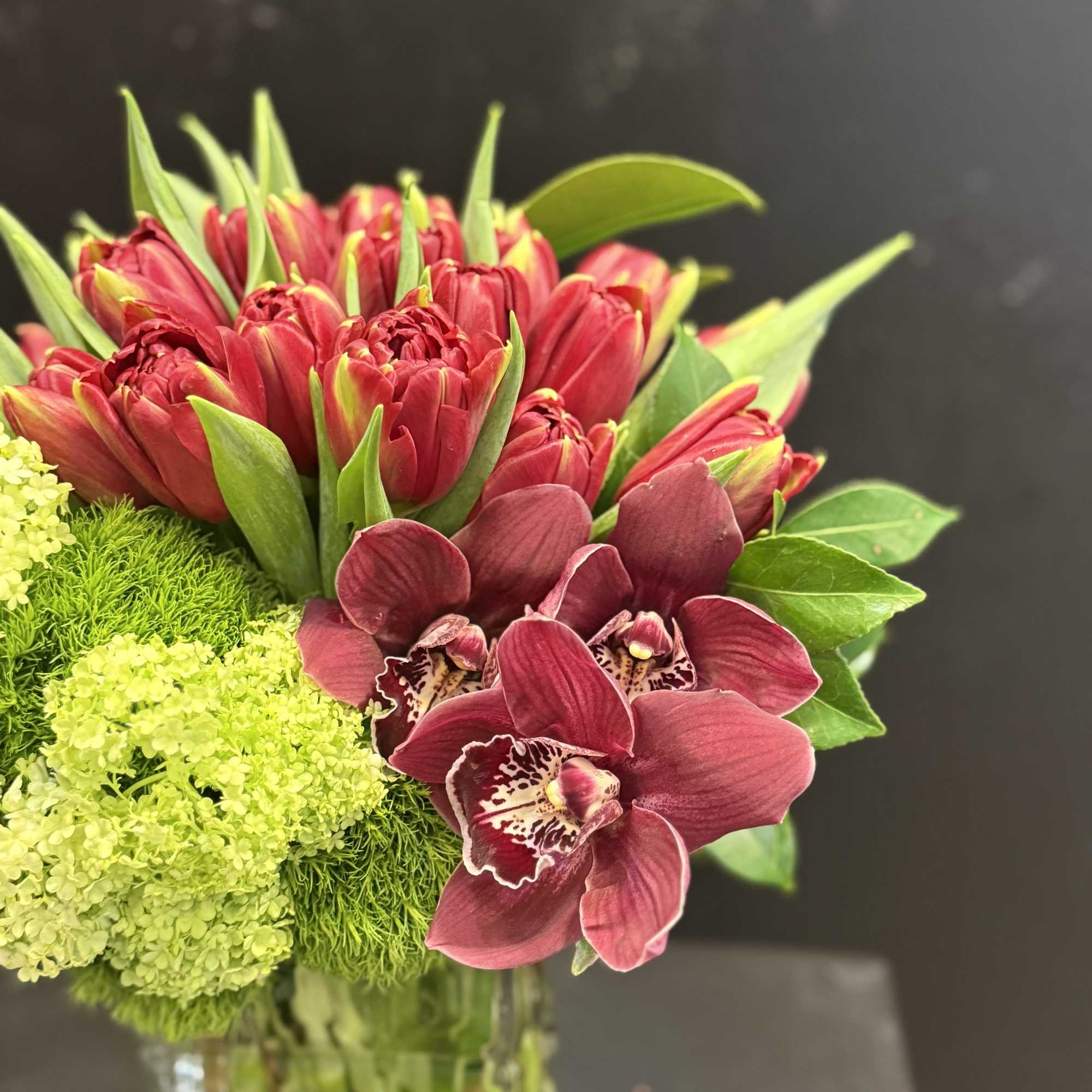 The Garnet Garden fresh floral arrangement blends rich red and burgundy tulips
