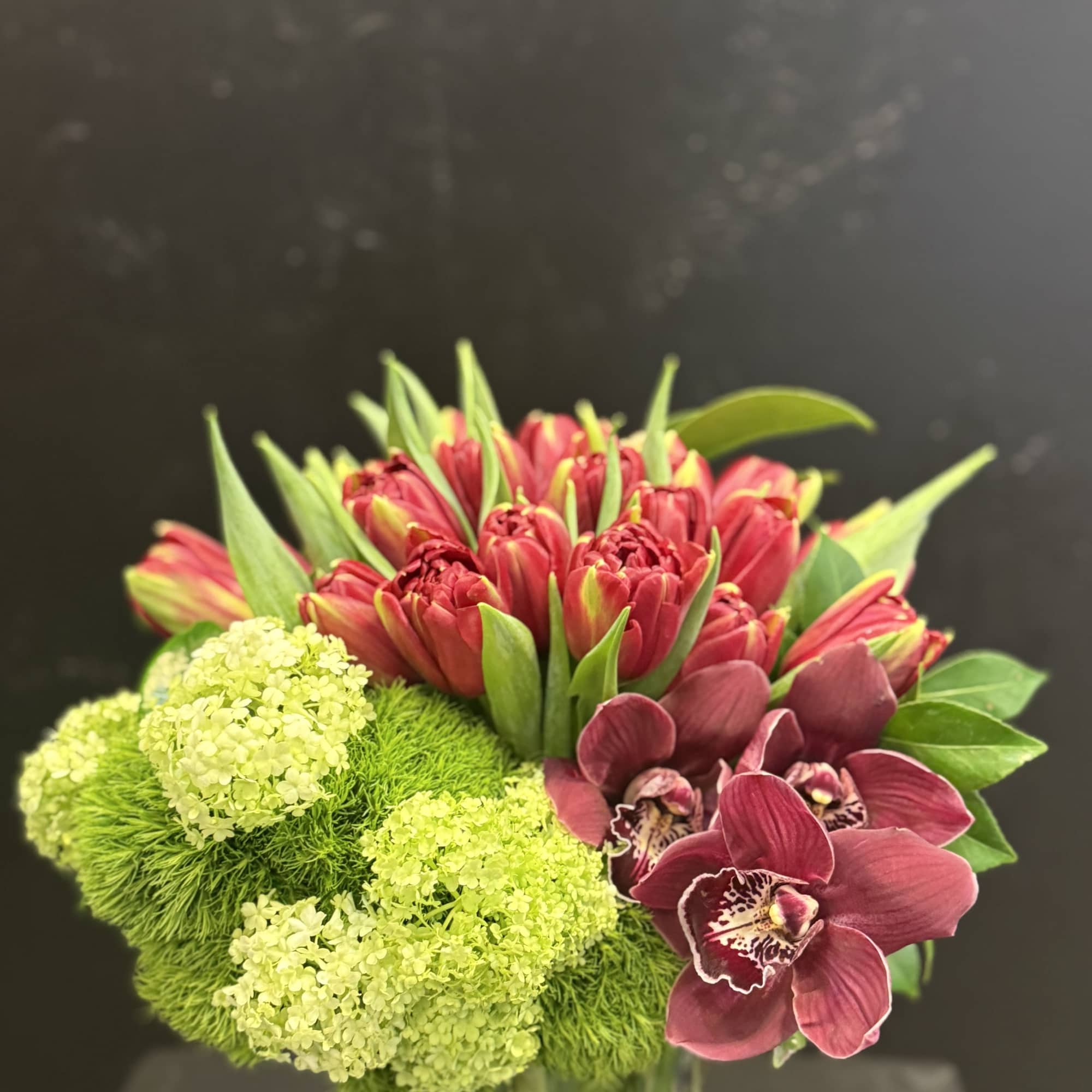 The Garnet Garden fresh floral arrangement blends rich red and burgundy tulips