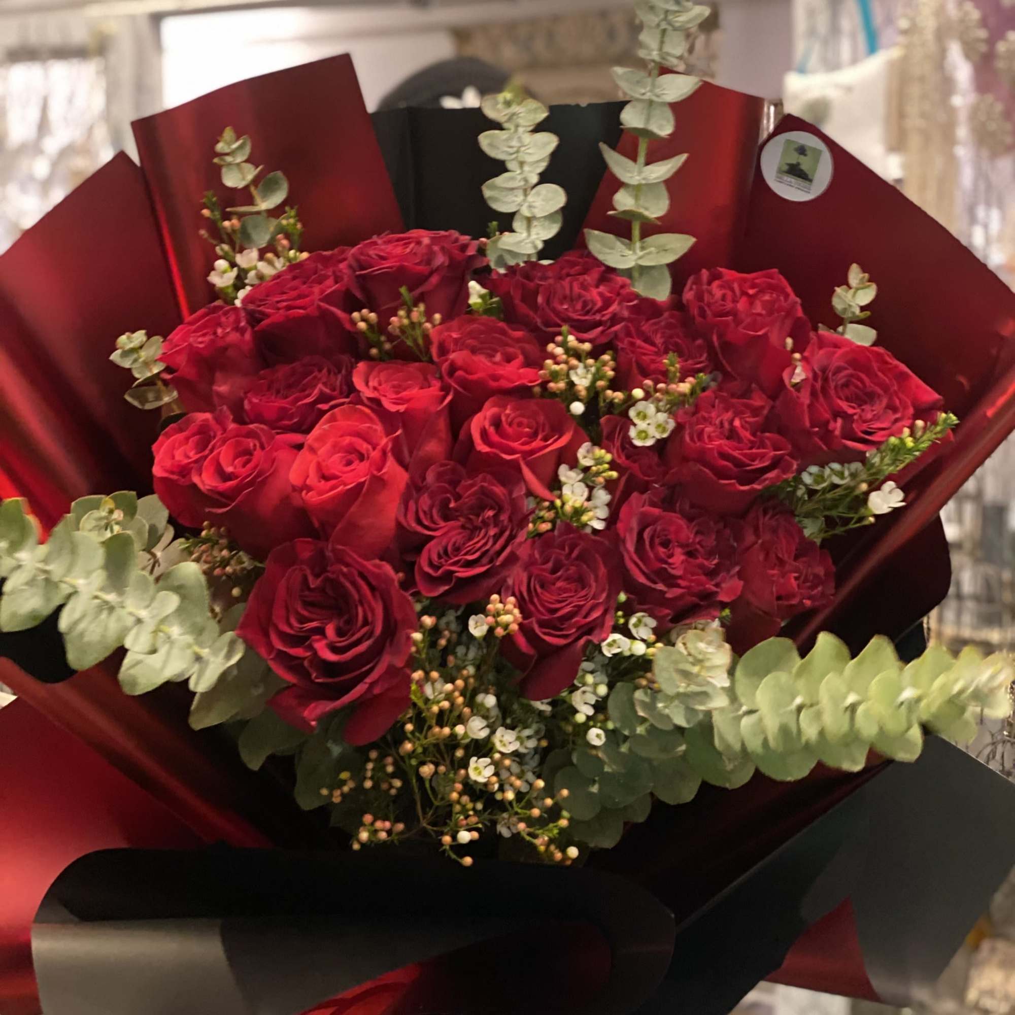 Bold red roses wrapped in deep burgundy paper(variety of colors), accented with