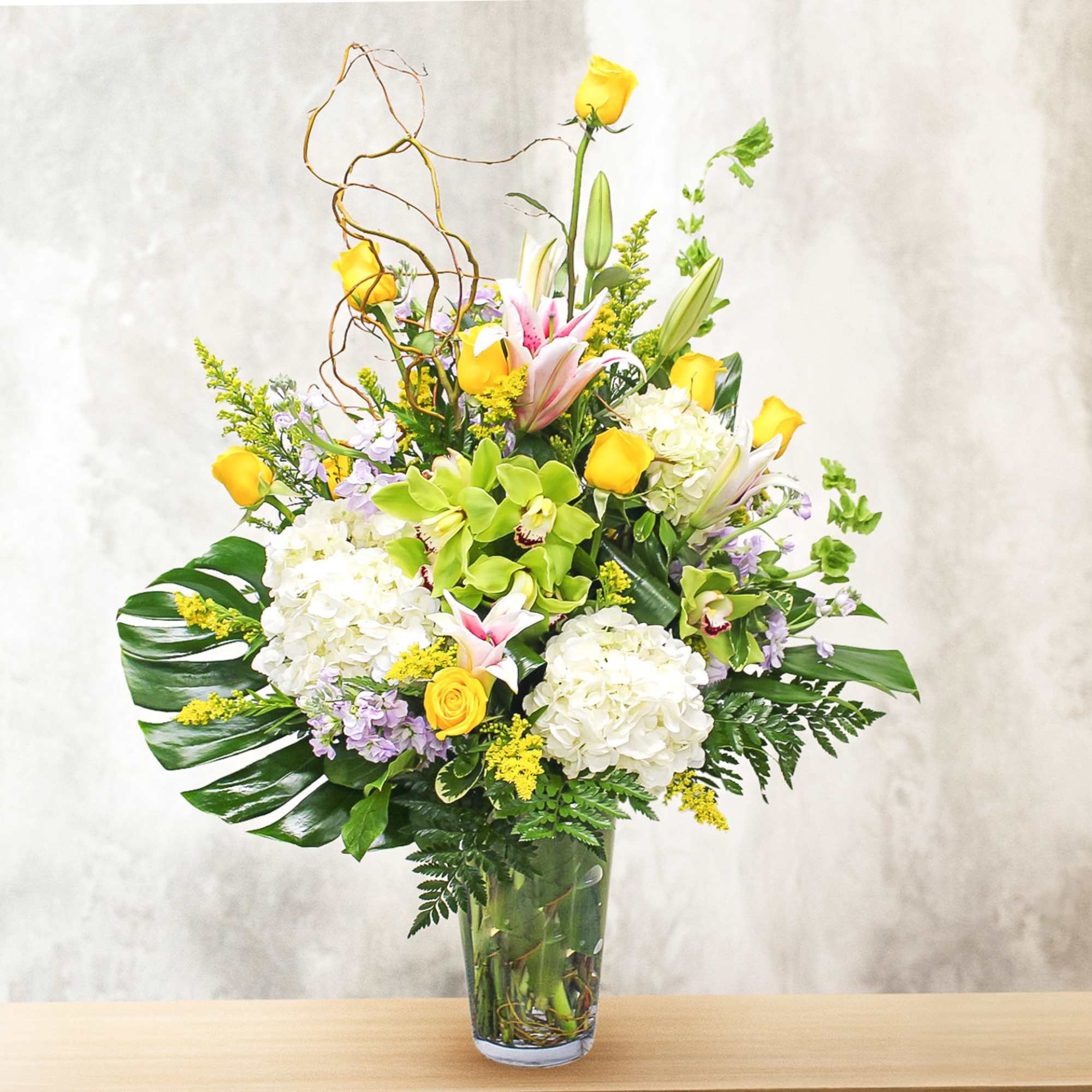 This unique design includes. stargazer lilies, yellow roses, hydrangea, lavender stock, cymbidium