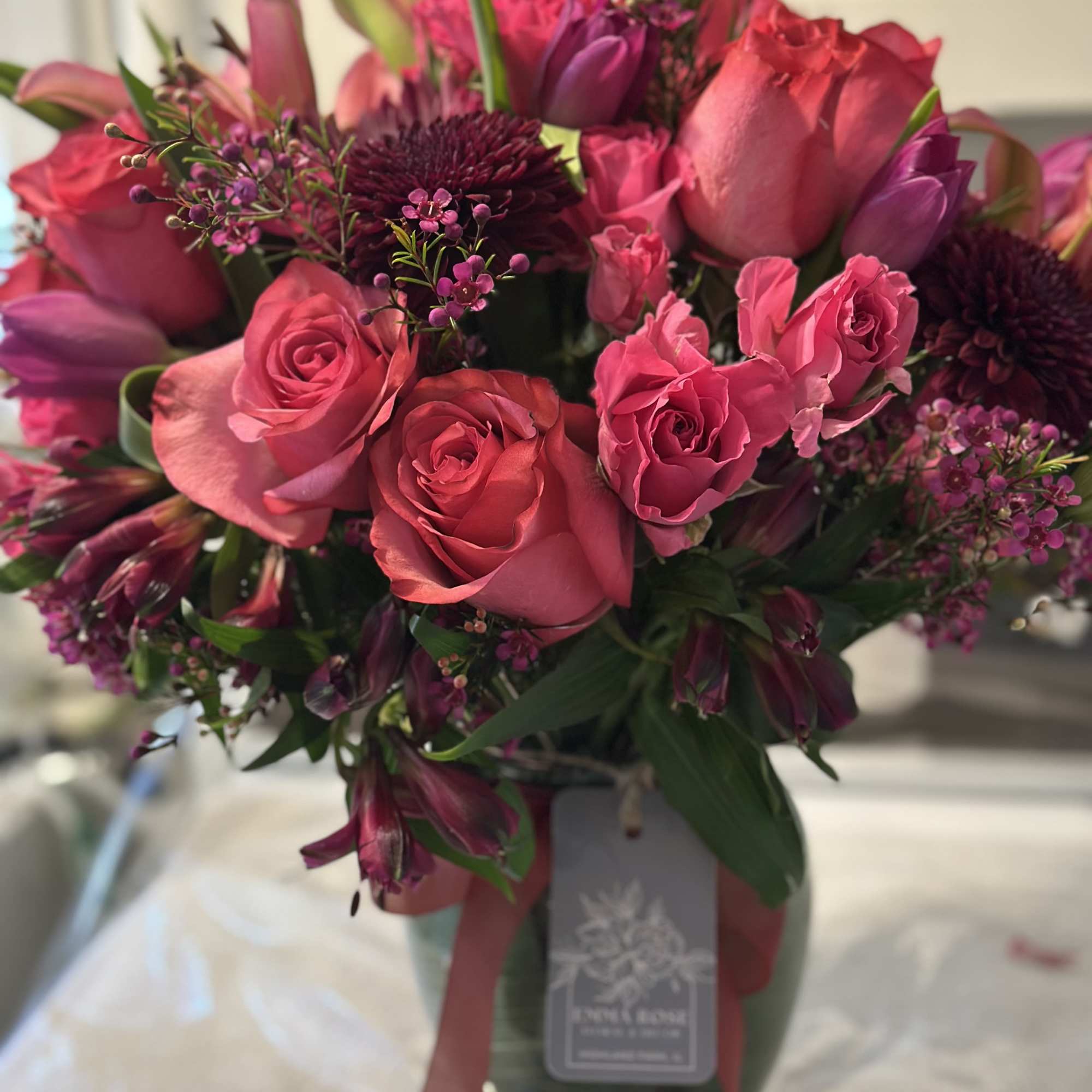 A lush bouquet of jewel-toned blooms arranged in a vase. 