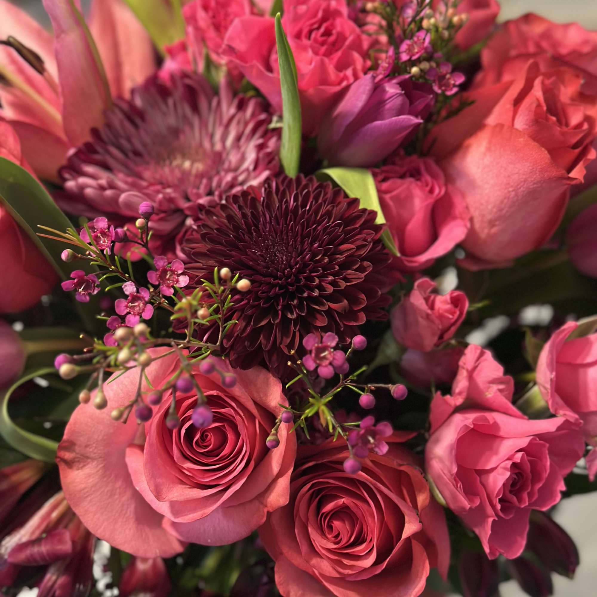 A lush bouquet of jewel-toned blooms arranged in a vase. 