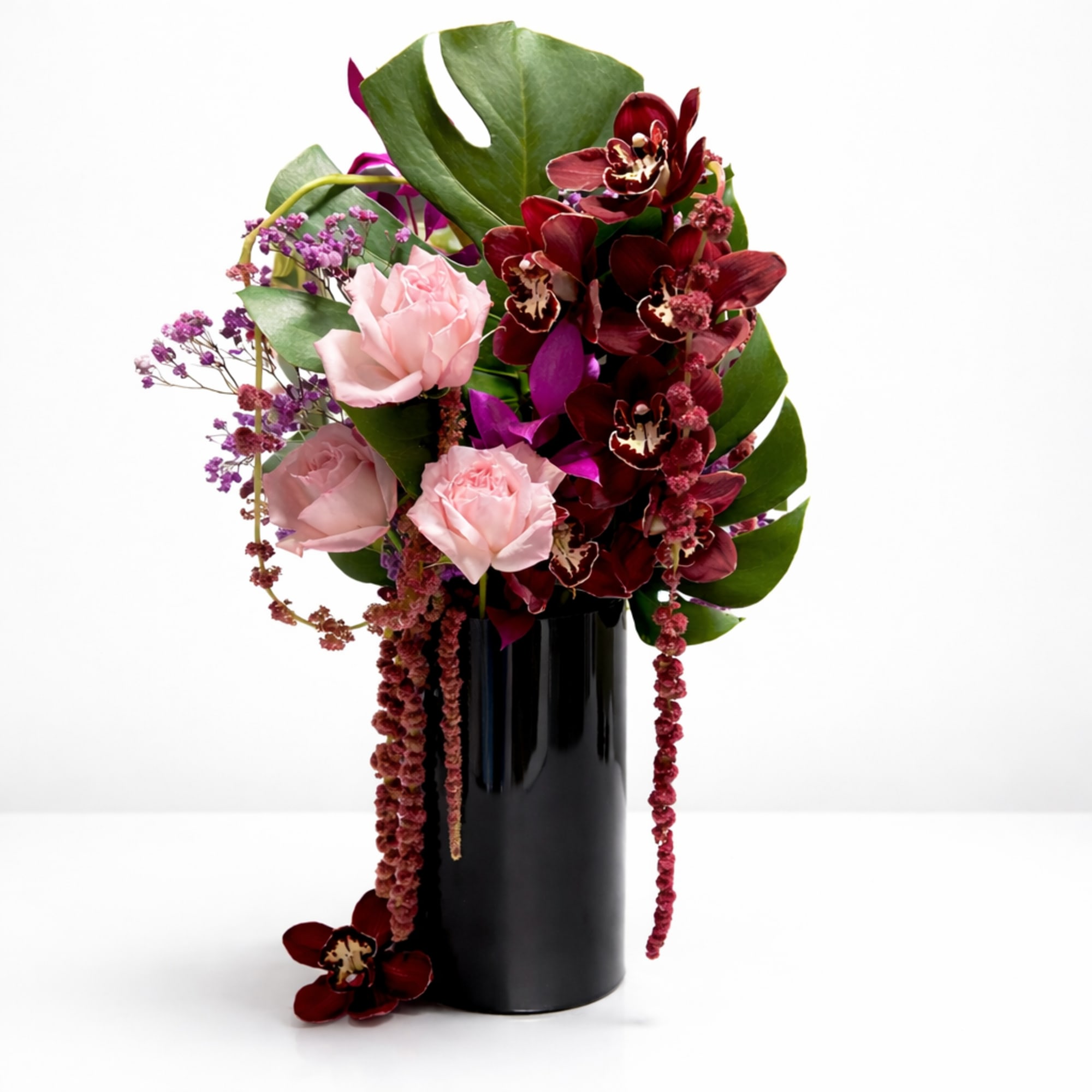 
A contemporary floral statement featuring burgundy orchids, blush roses, cascading textures, and