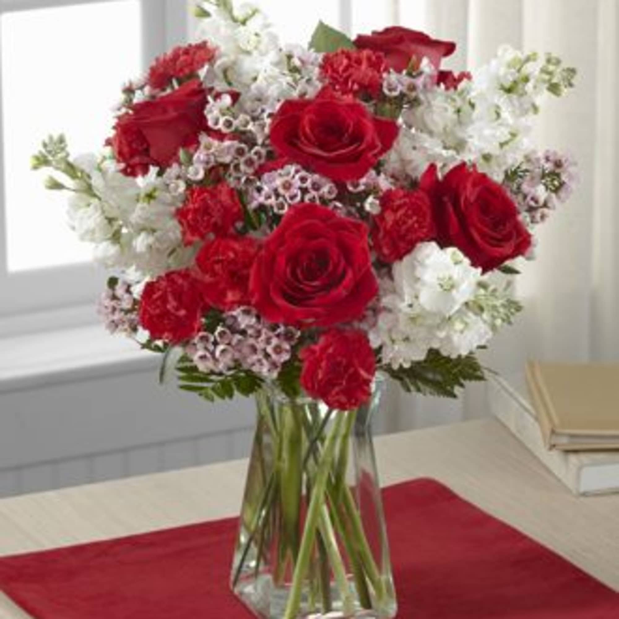 ROSES, STOCK AND MINI CARNATIONS IN A CLEAR VASE.

