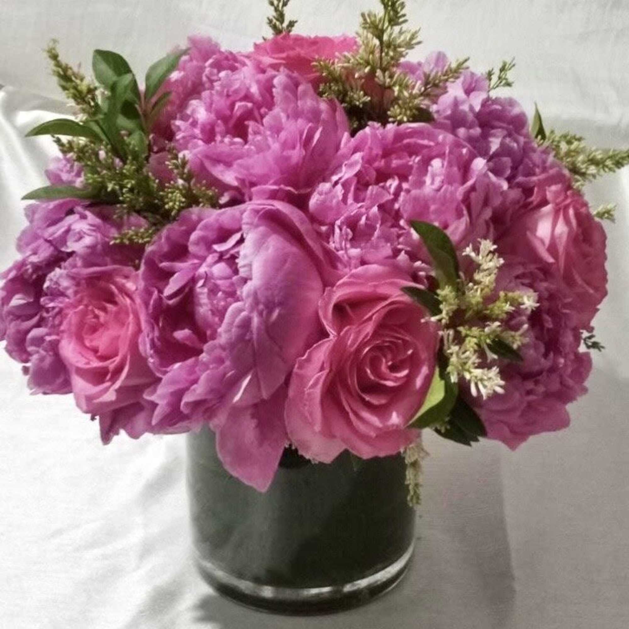 This arrangement is made up of pink roses and pink peonies. Vase