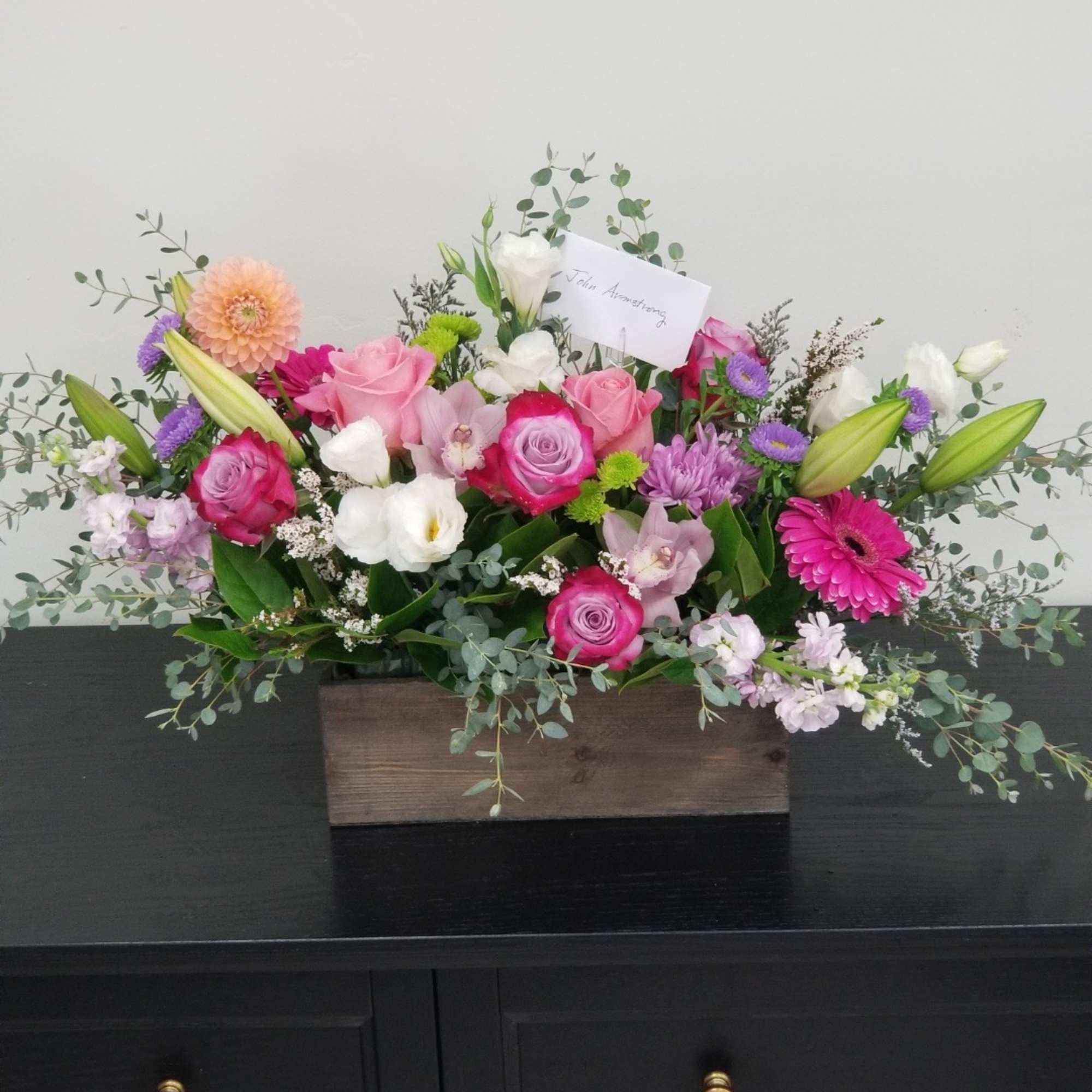 Beautiful combination of roses, lilies, spray roses, pom poms in a wooden