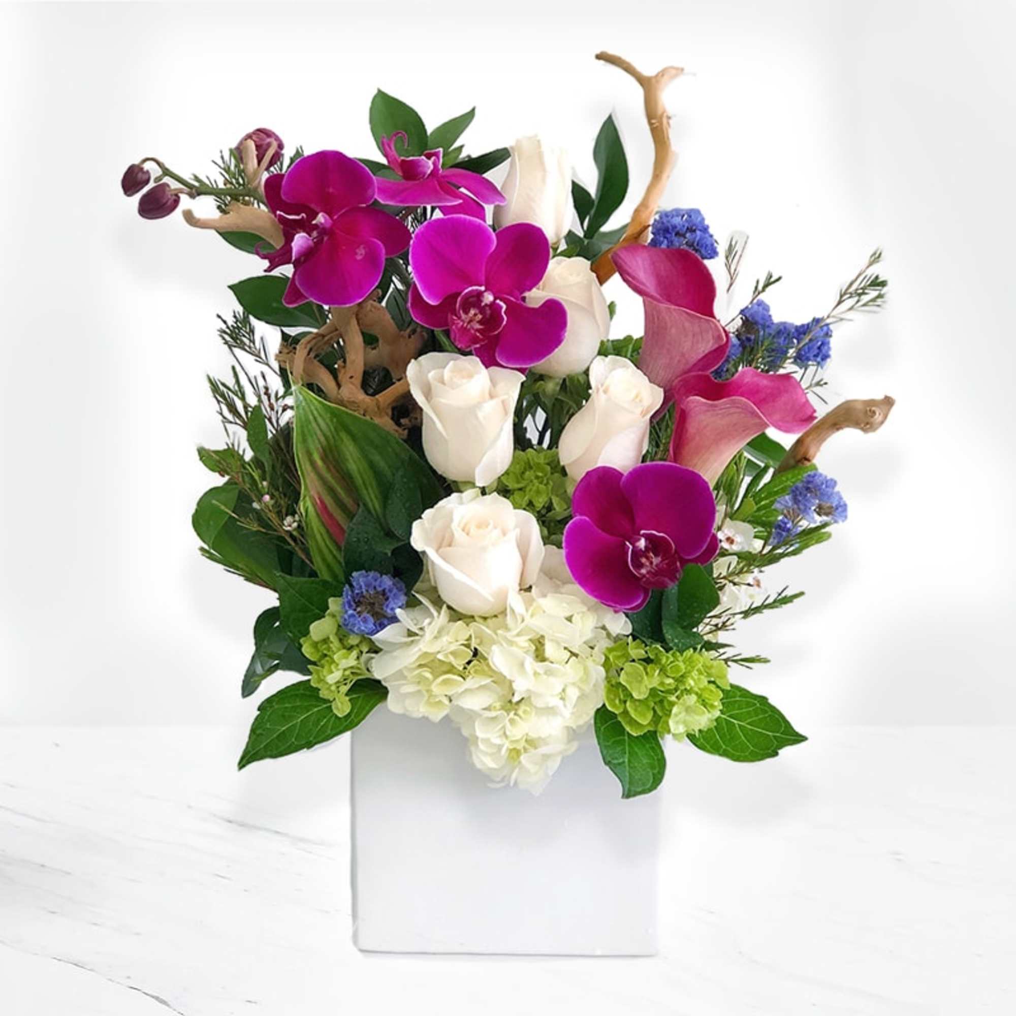 Crystal Cove arrangement handcrafted with Phalaenopsis orchids, white roses, purple mini Calla