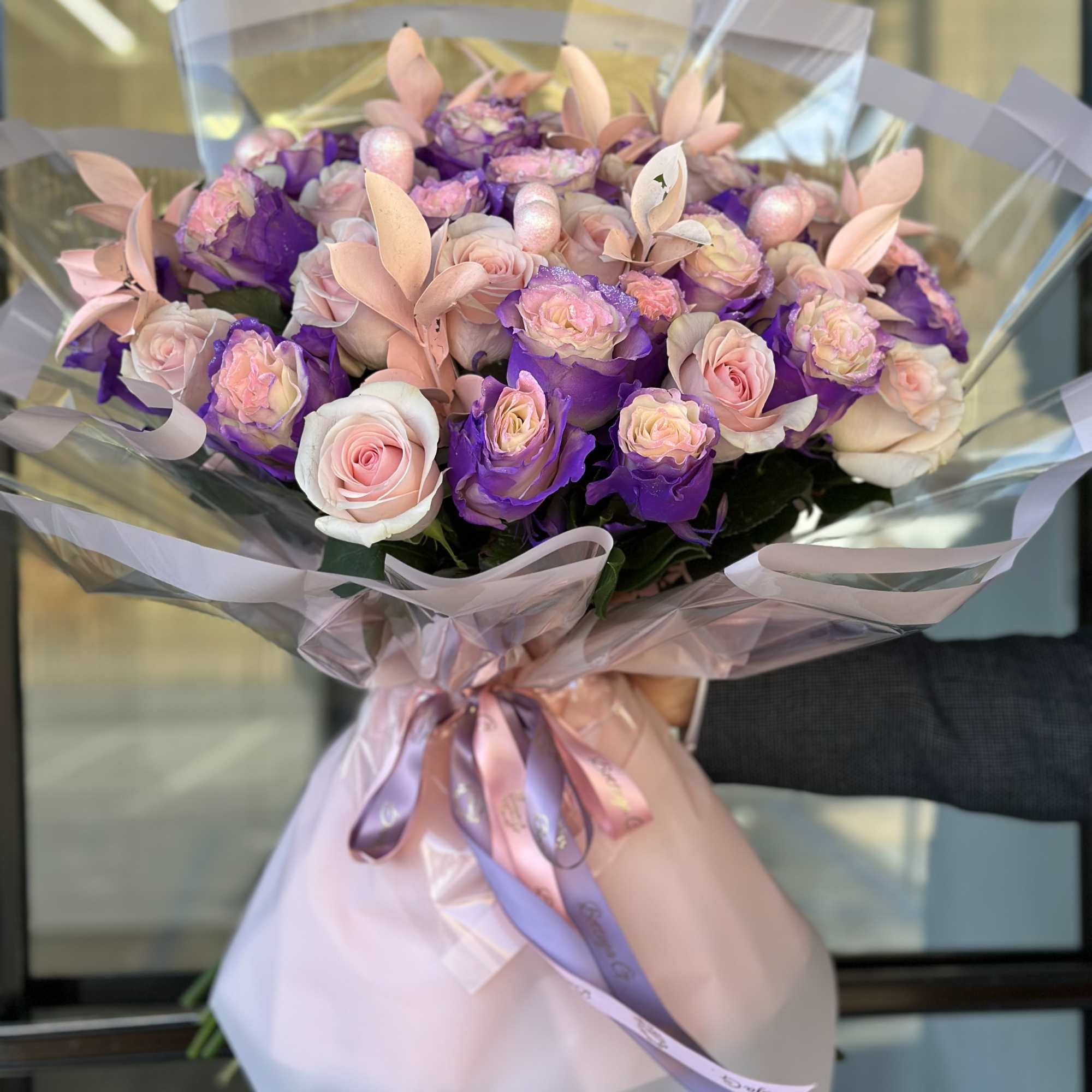 Composition: The bouquet features a variety of pink and purple roses as