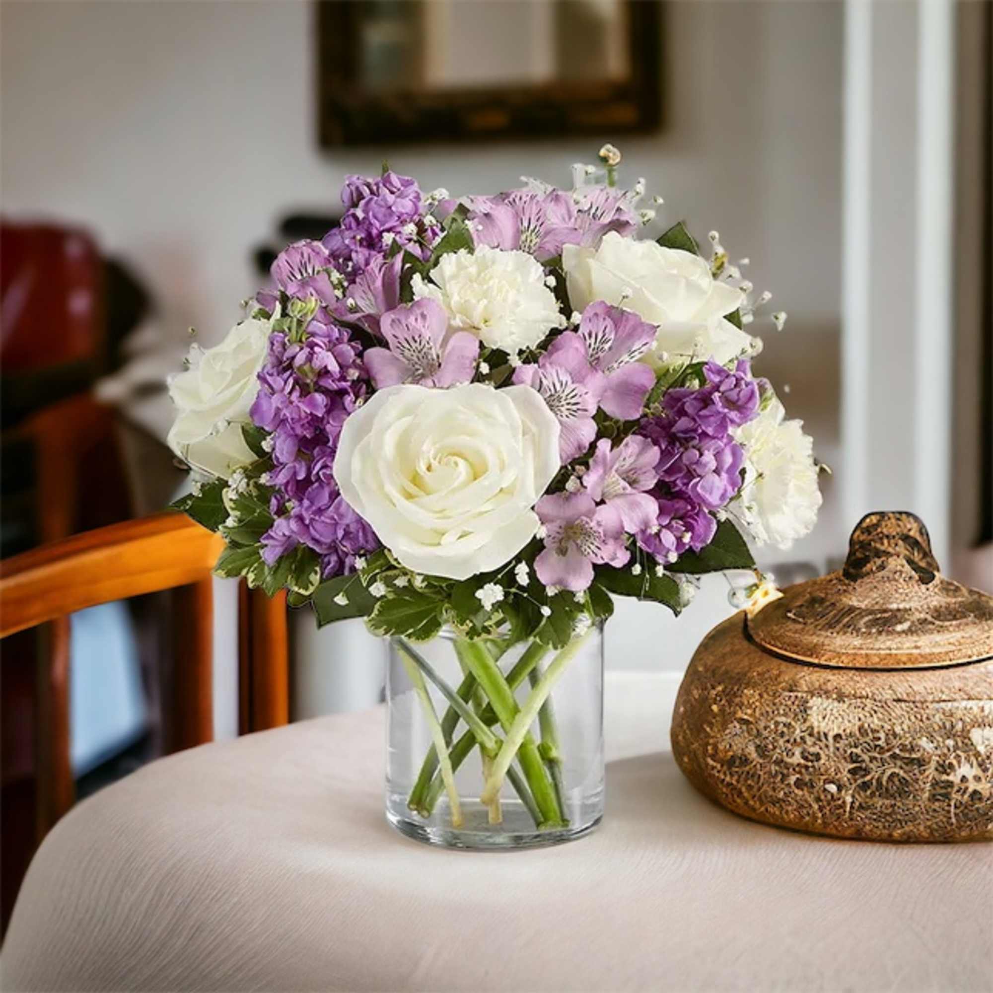 White roses, white carnations, lavender Astro, purple stock, baby&rsquo; breath and greenery