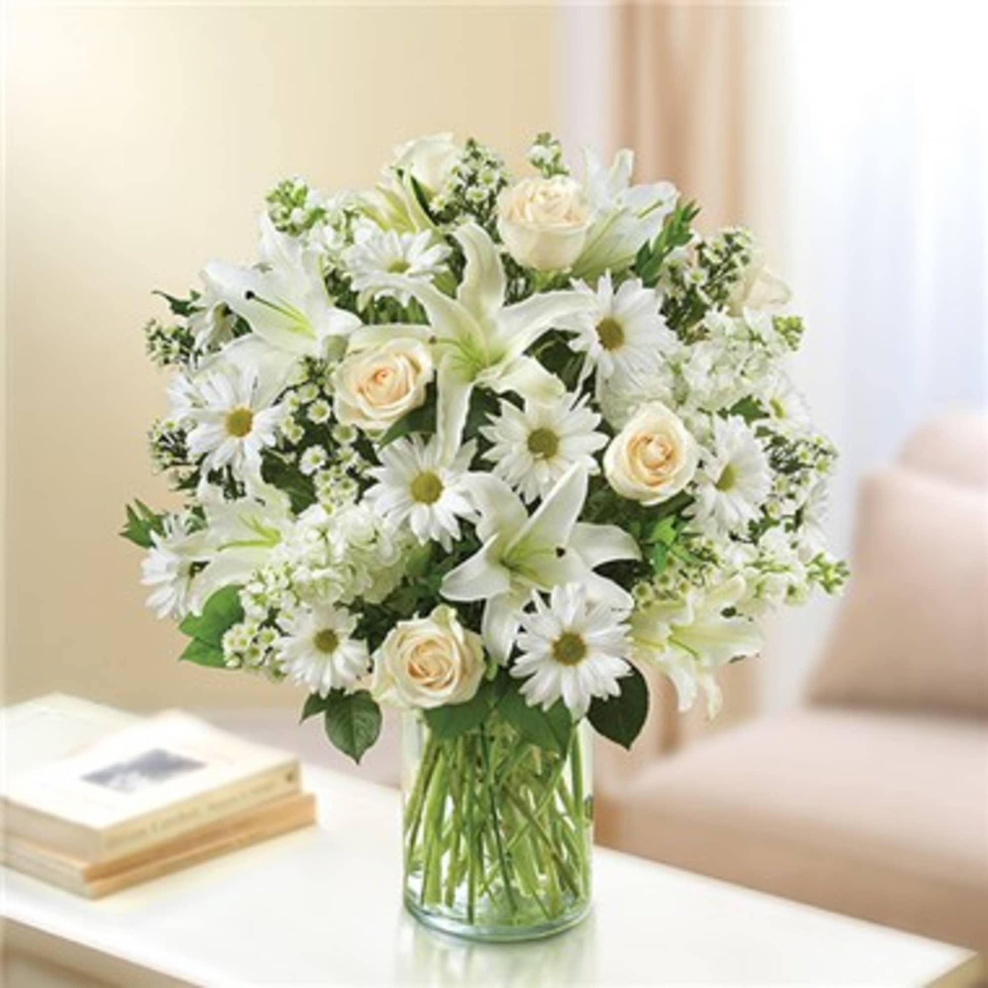 Express your sincere condolences with our elegant all-white arrangement of roses, lilies
