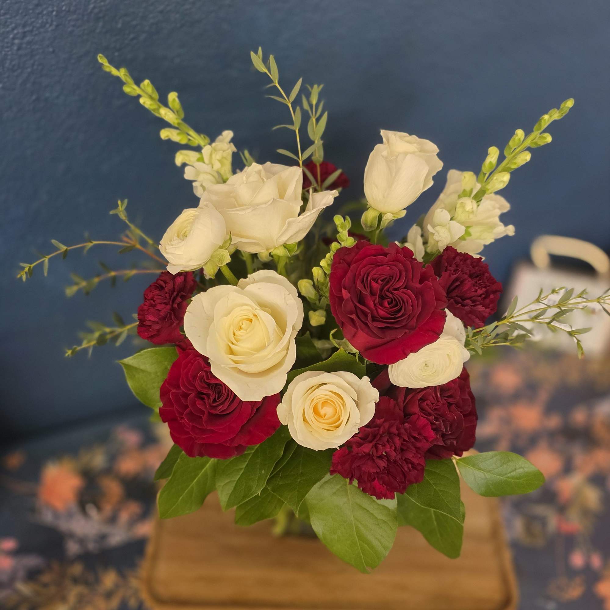 The Burgundy Beauty is a rich design with snap dragons, white roses