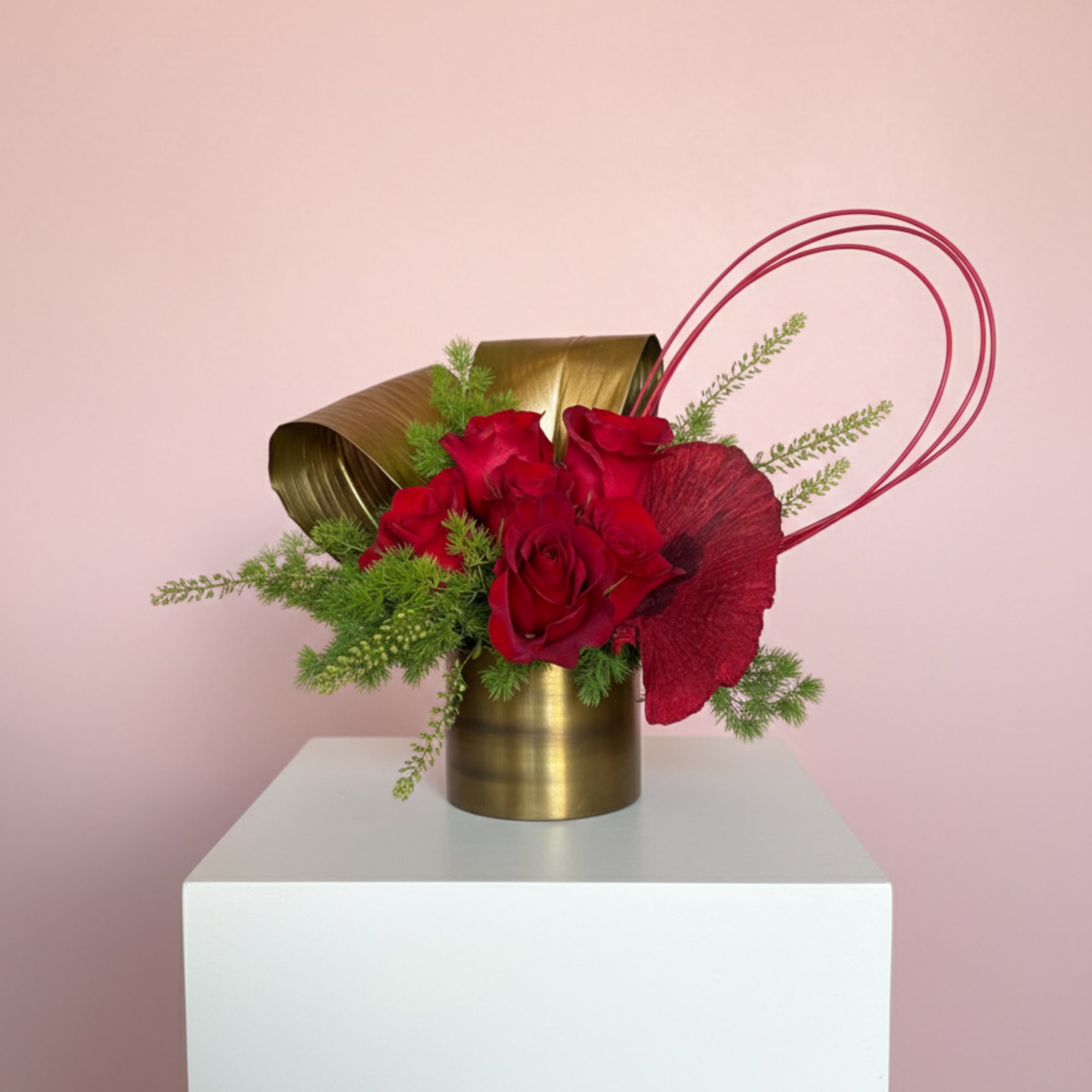 Red roses anchor this arrangement, surrounded by flowing lines and fresh green