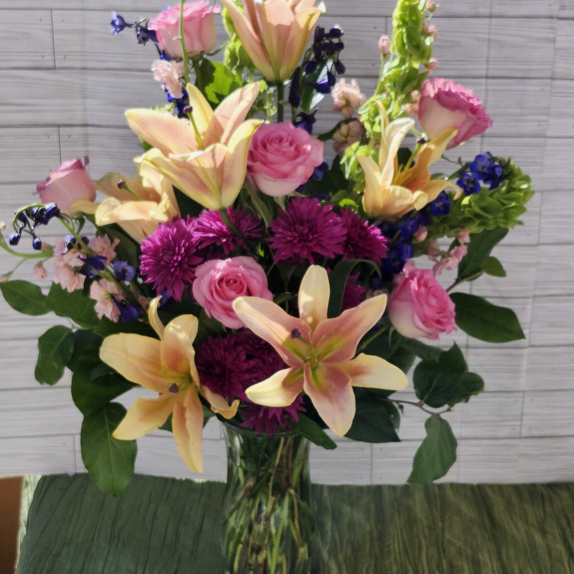 This arrangement contains stargazer lilies, bells of ireland, stock, blue iris, roses