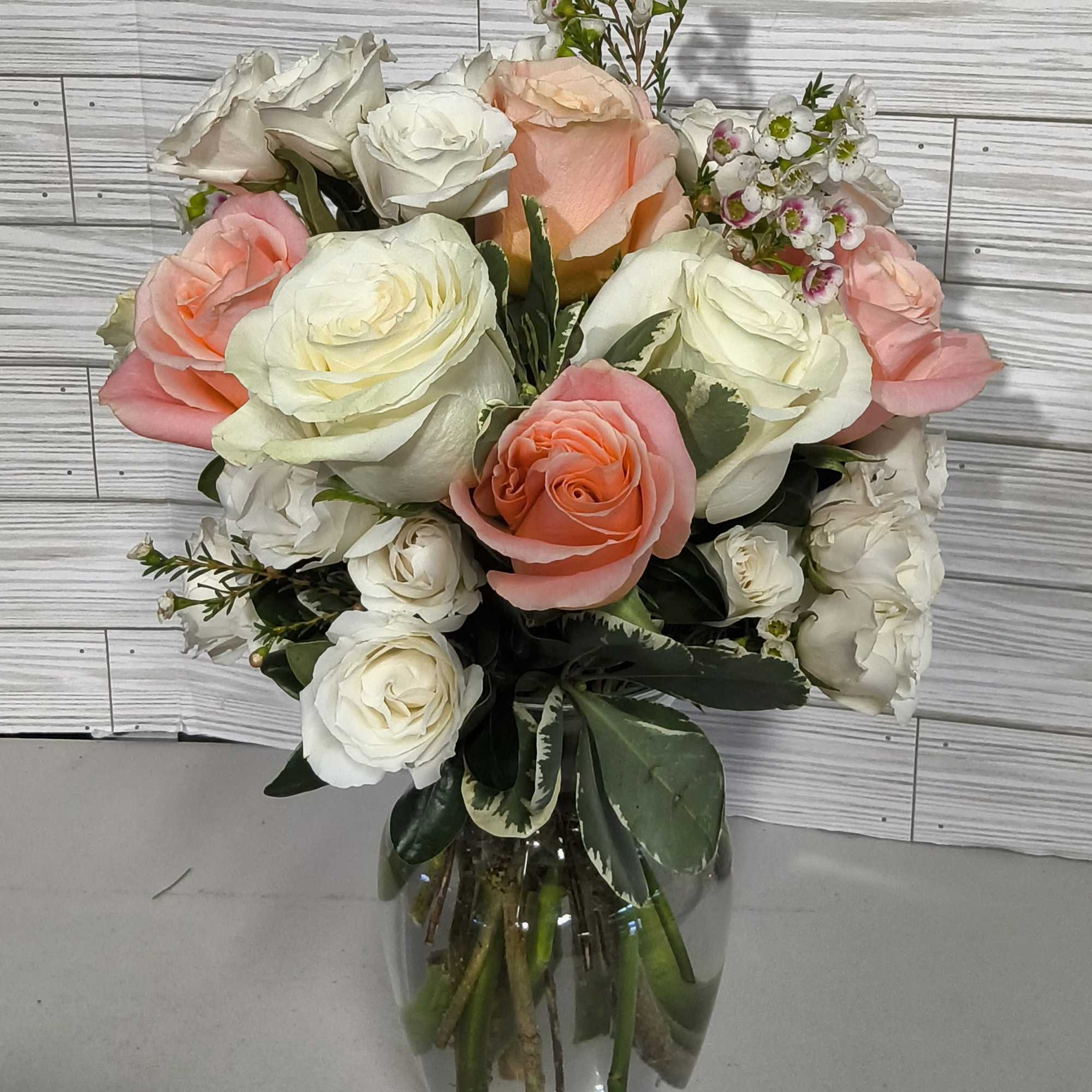 This arrangement includes pink roses, white roses, white spray roses, pink carnations
