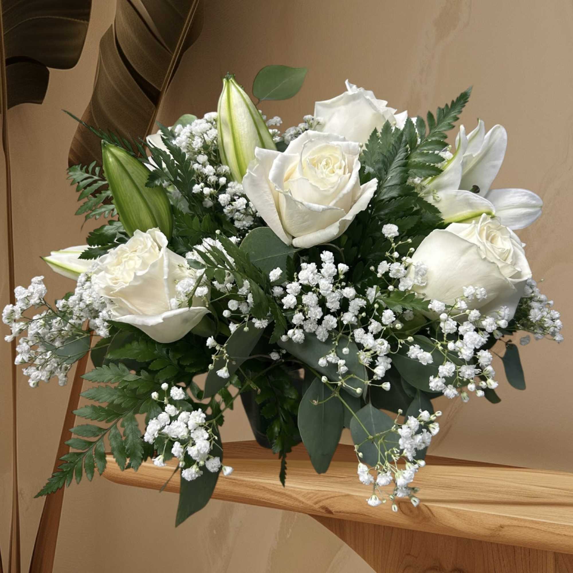 A graceful arrangement of white roses, lilies, and baby&rsquo;s breath, symbolizing purity