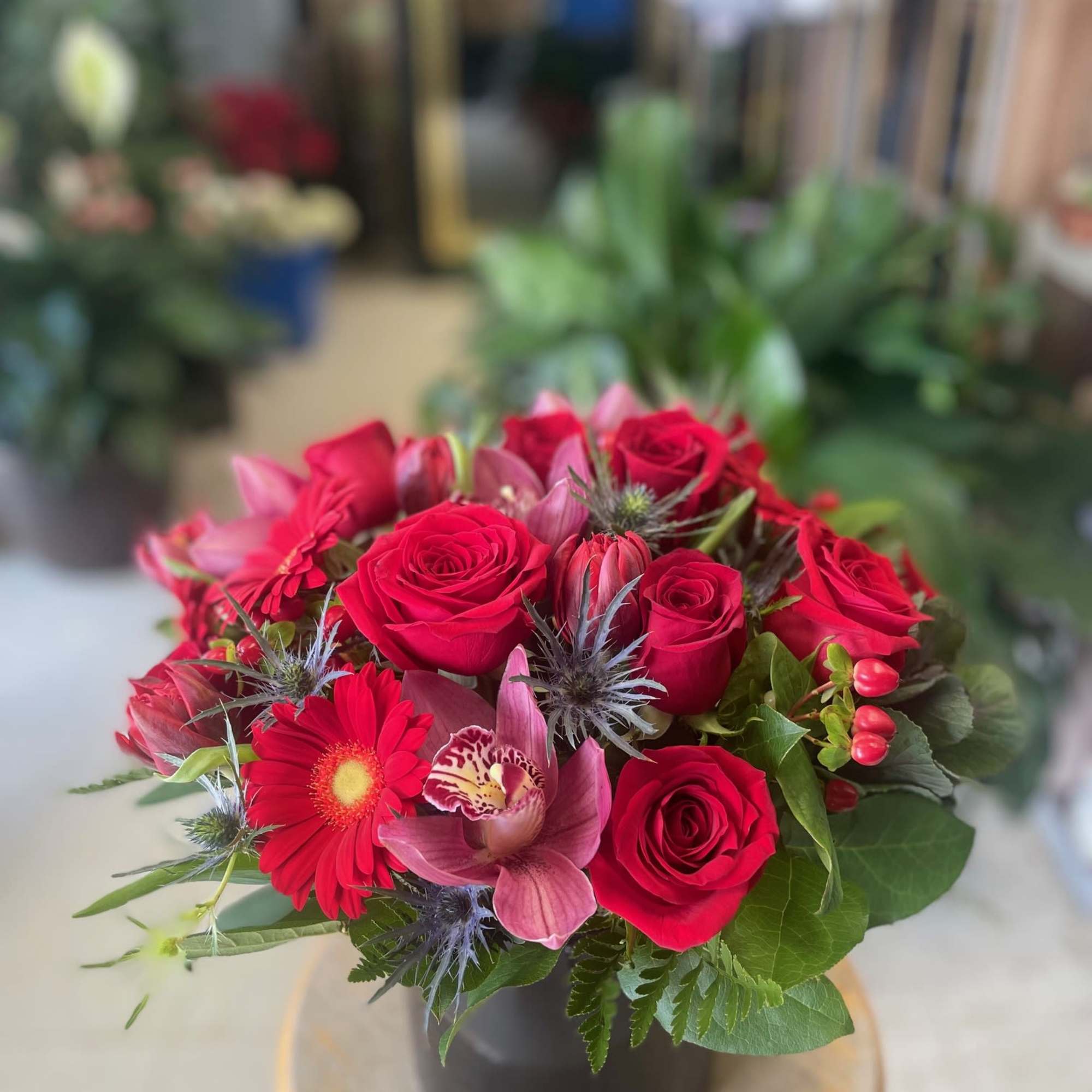 Red roses, Red Gerbera Daisy, Red Tulips, Blue Thistles, Red berries, Pink