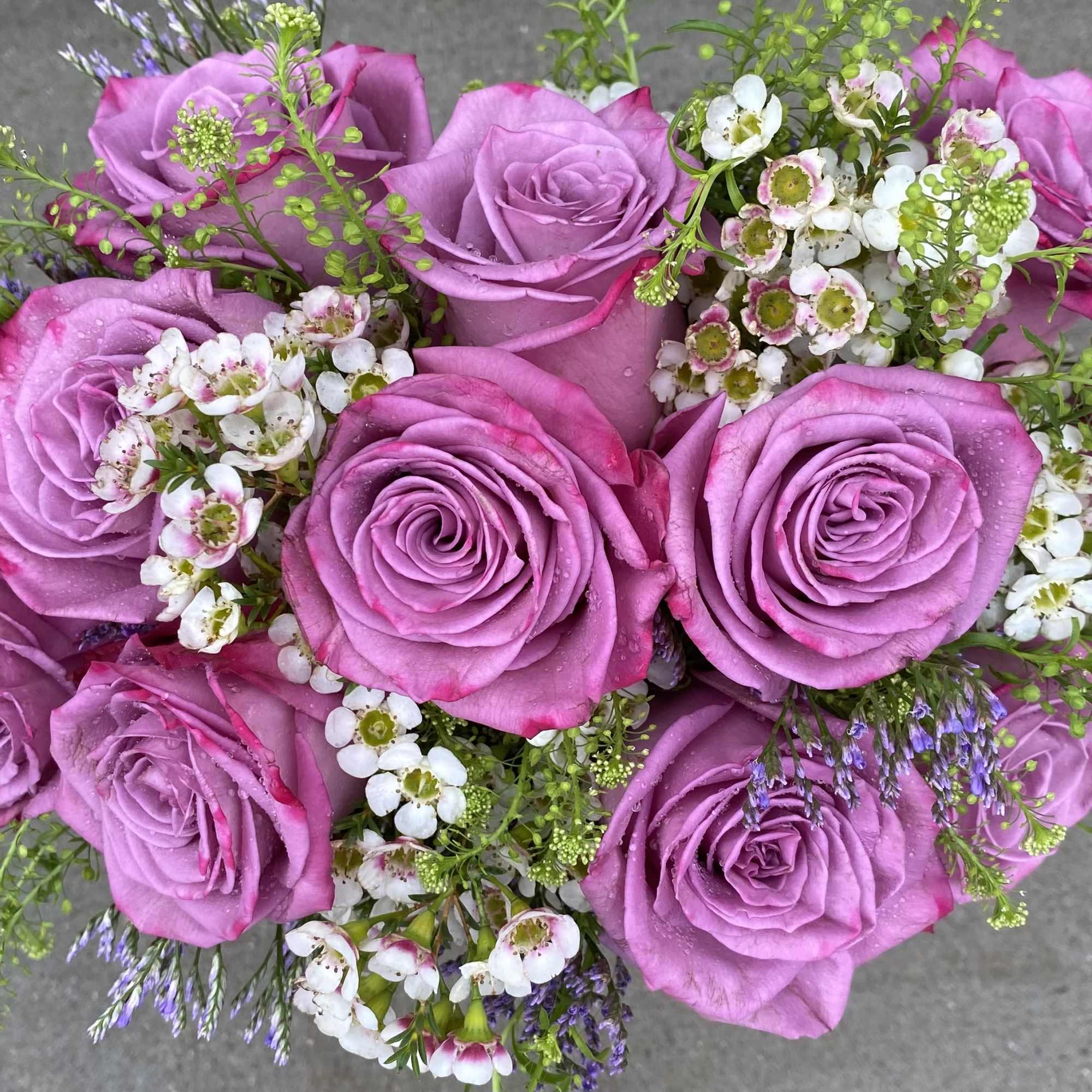 A Dozen Lavender Roses with accent flowers in a Pink and Beige