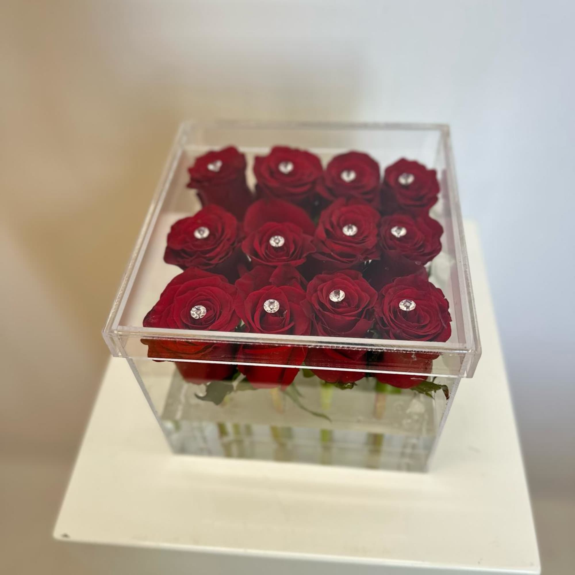 Red roses in a clear square box with small crystal accents