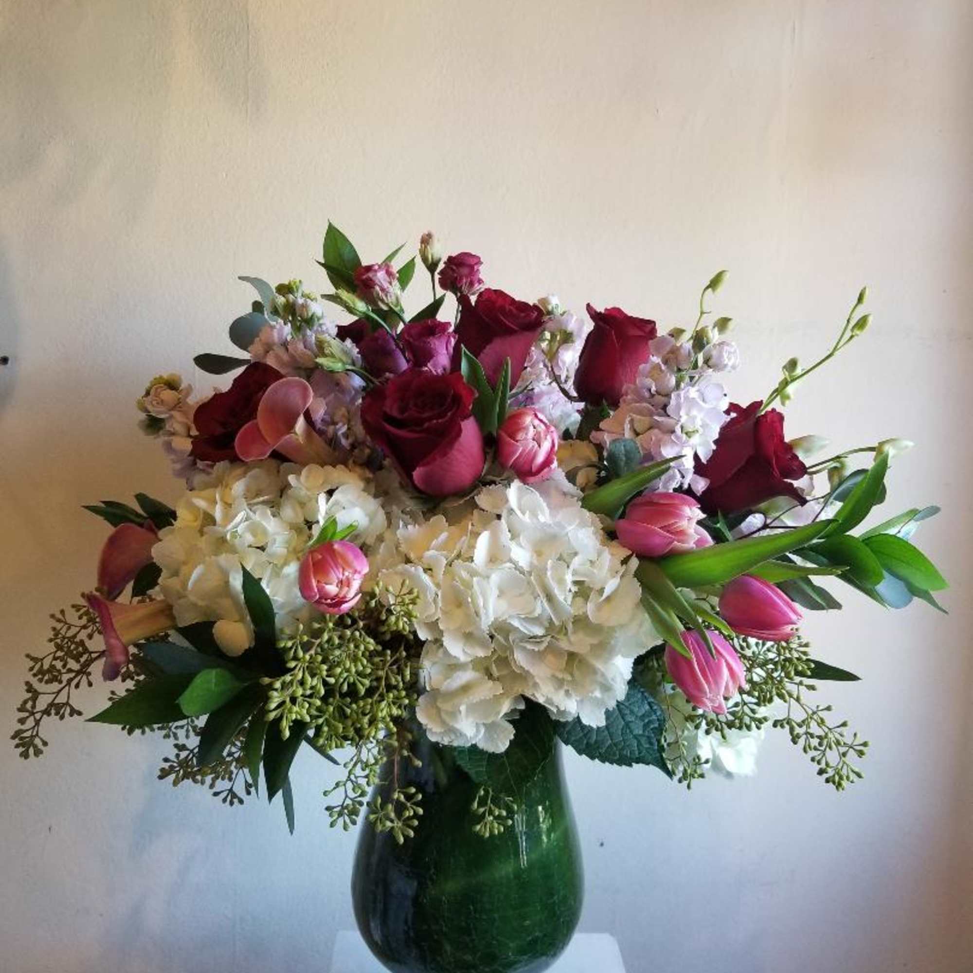 A mixture of pink, red and white flowers, including roses, hydrangea, stock