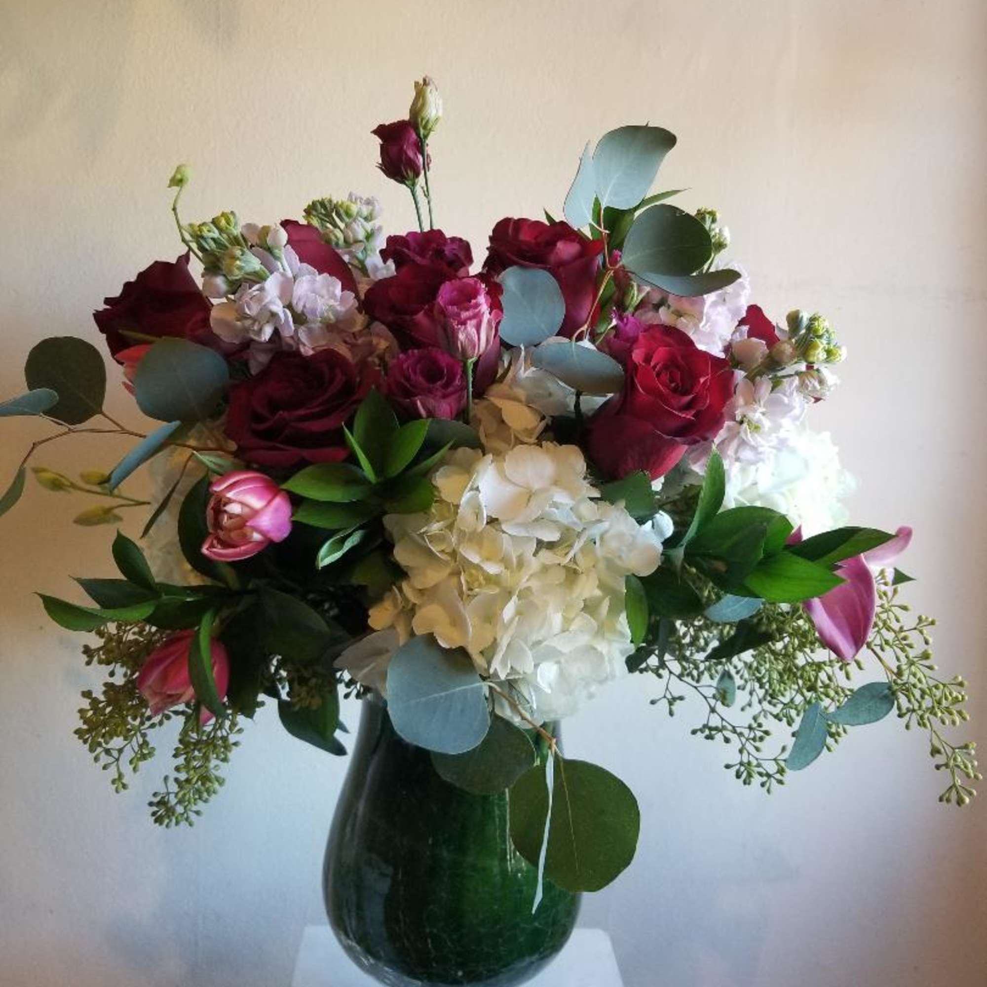 A mixture of pink, red and white flowers, including roses, hydrangea, stock
