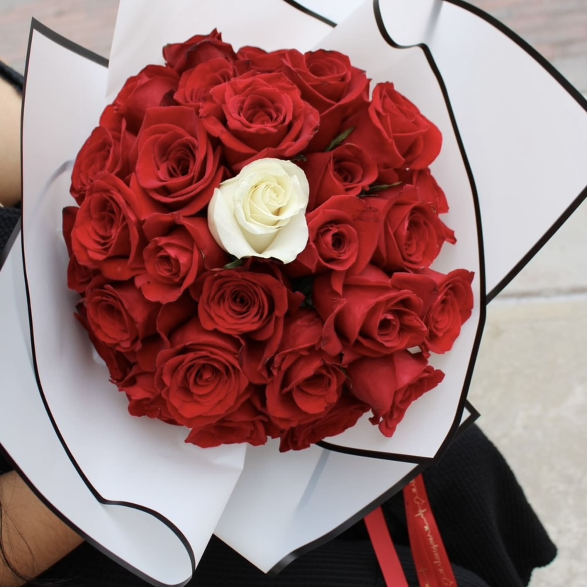 Red and white roses, wrapped in white and black paper Glass vase
