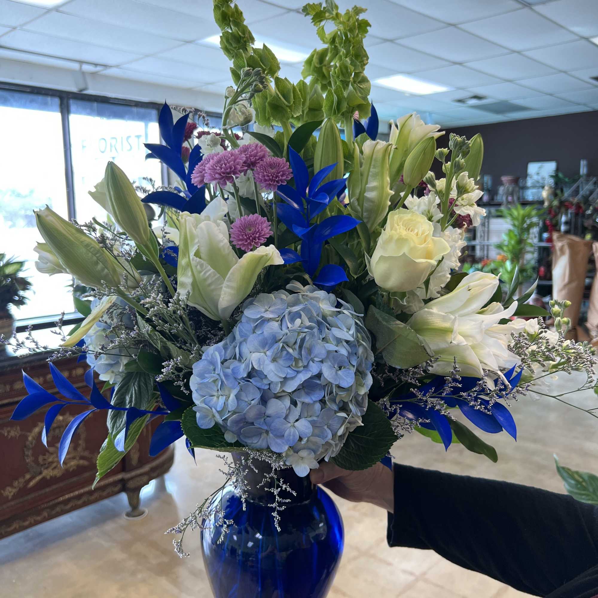 This arrangement is composed of blue thistle, blue hydrangeas, white lilies, white