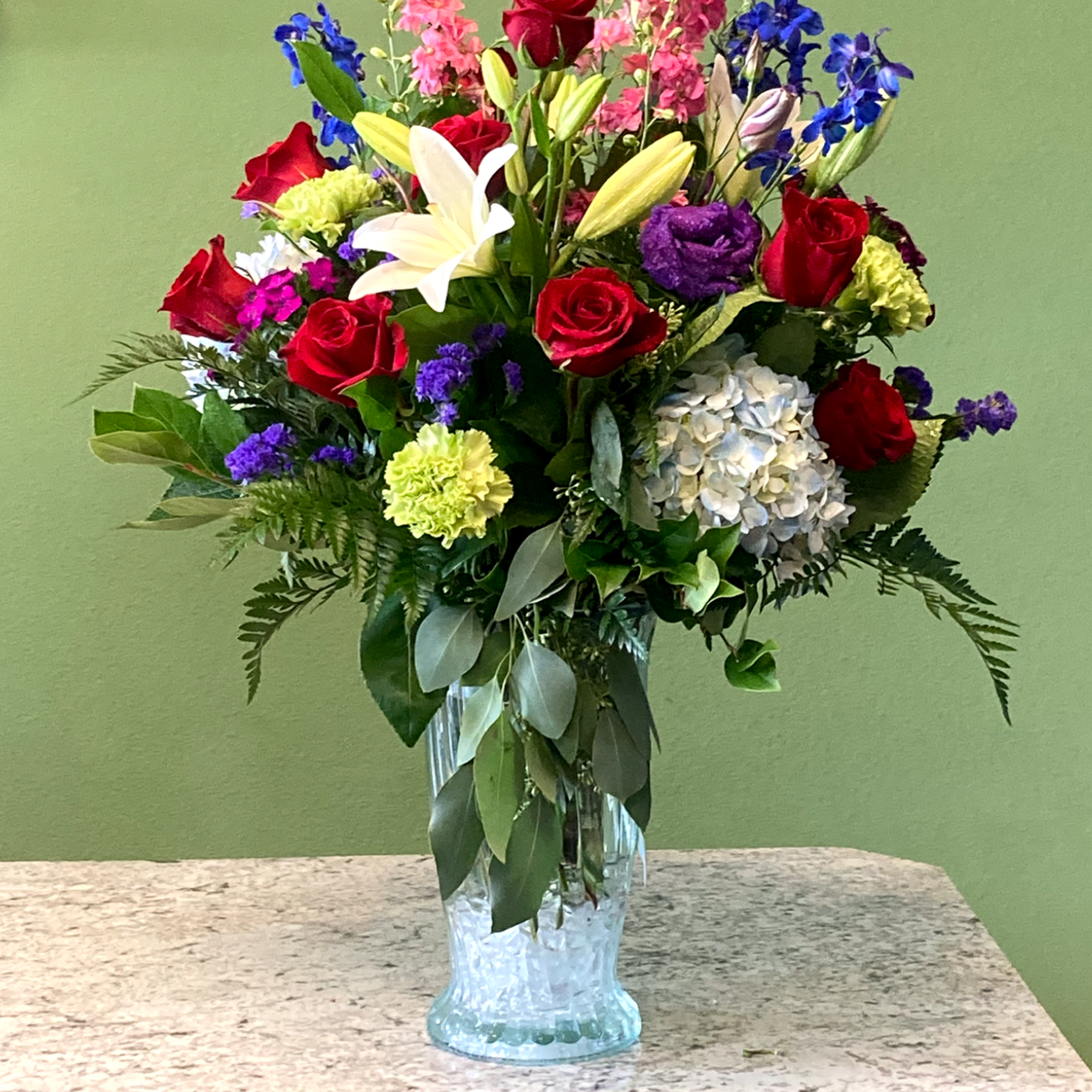 A beautiful arrangement, featuring one dozen (12) premium red roses, blended with