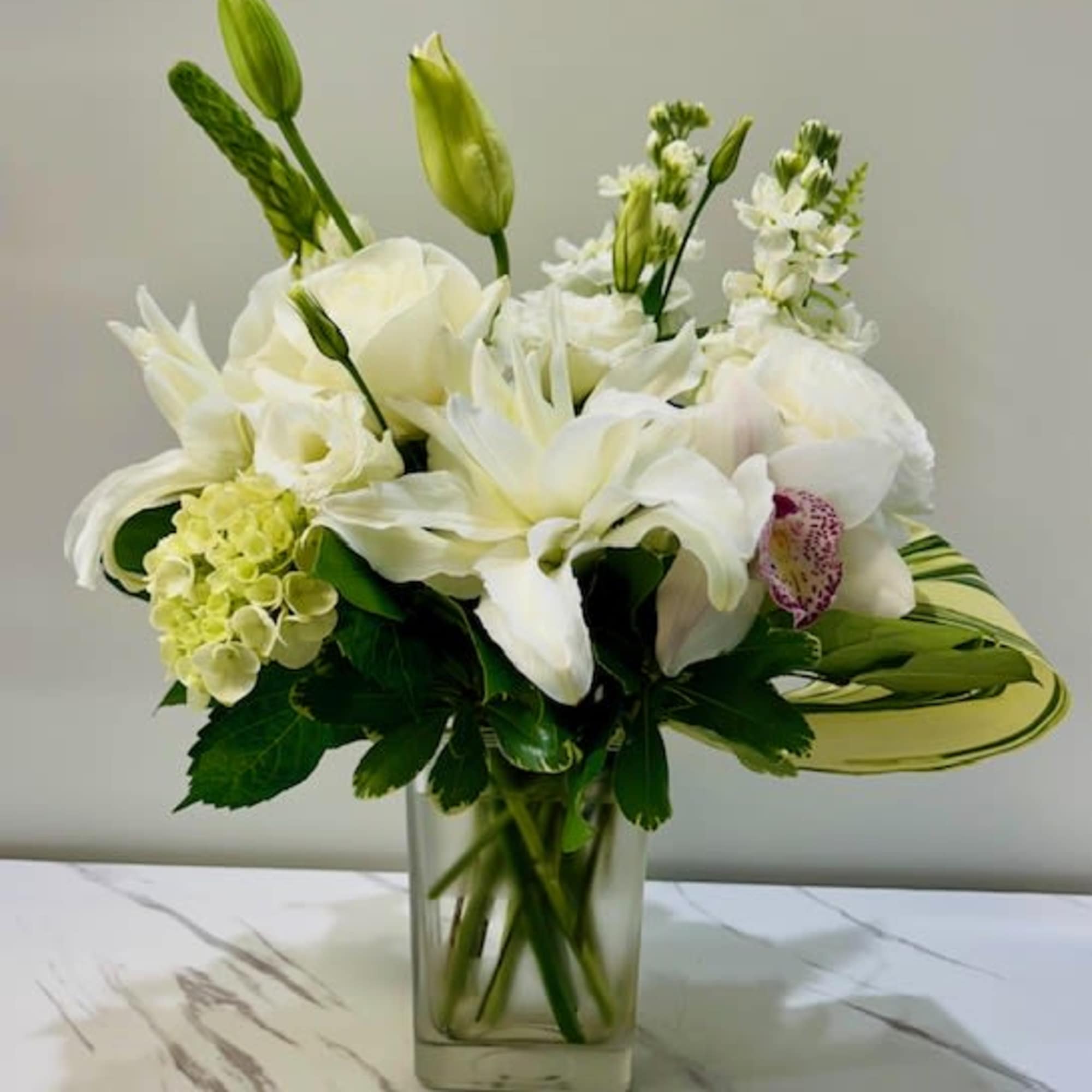 A modern, all-white arrangement featuring fresh blooms with elegant simplicity. Chic Blanc