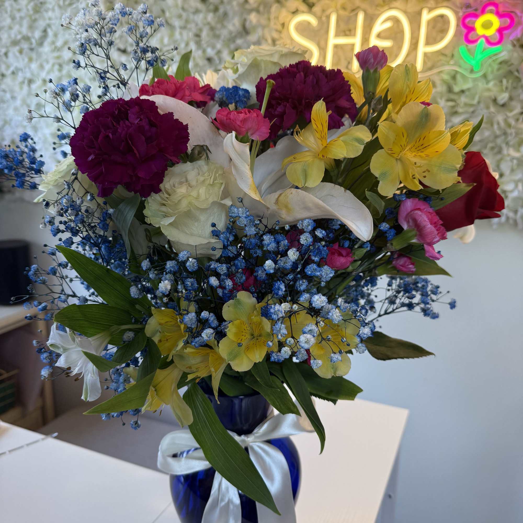 Beautiful mix flowers with blue baby breath in a classic blue vase.
