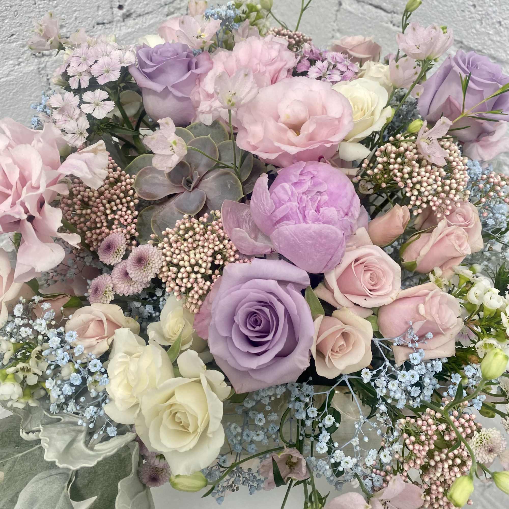 Square wooden box filled with all pastel flowers. 