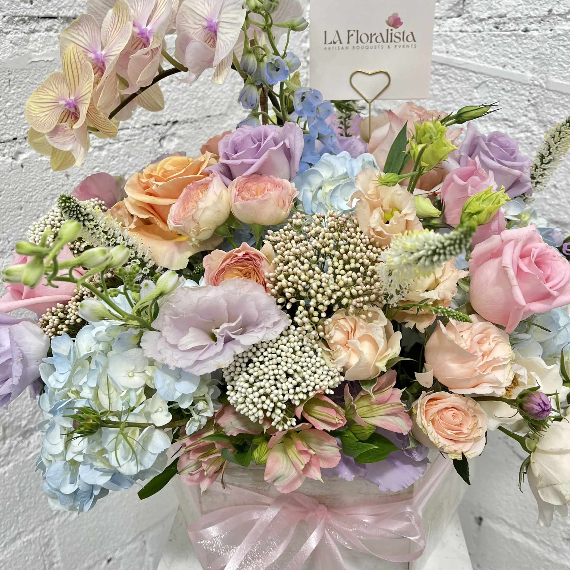 Square wooden box filled with all pastel flowers. 