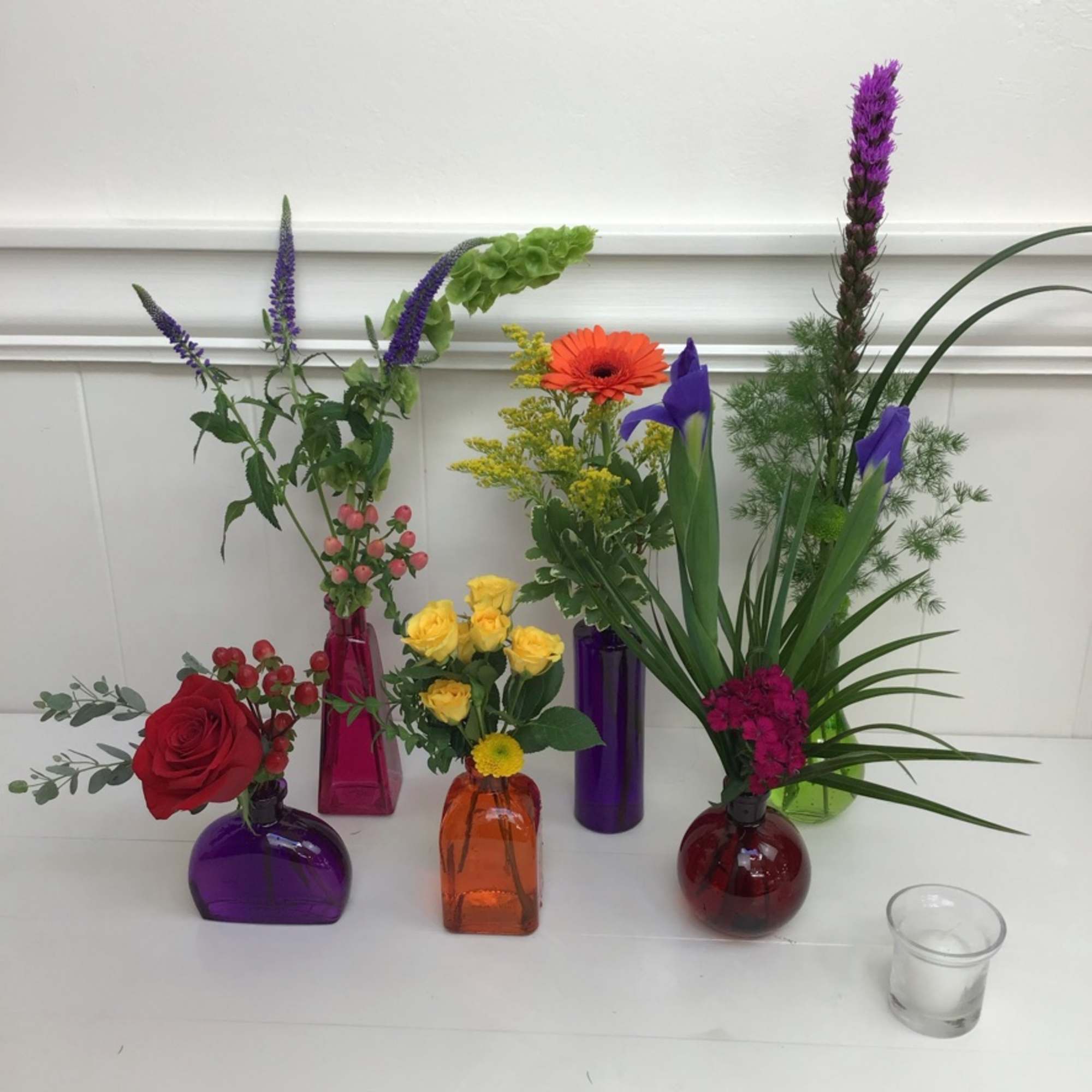 Six charming assorted colored vases, each accented with a different flower, filler