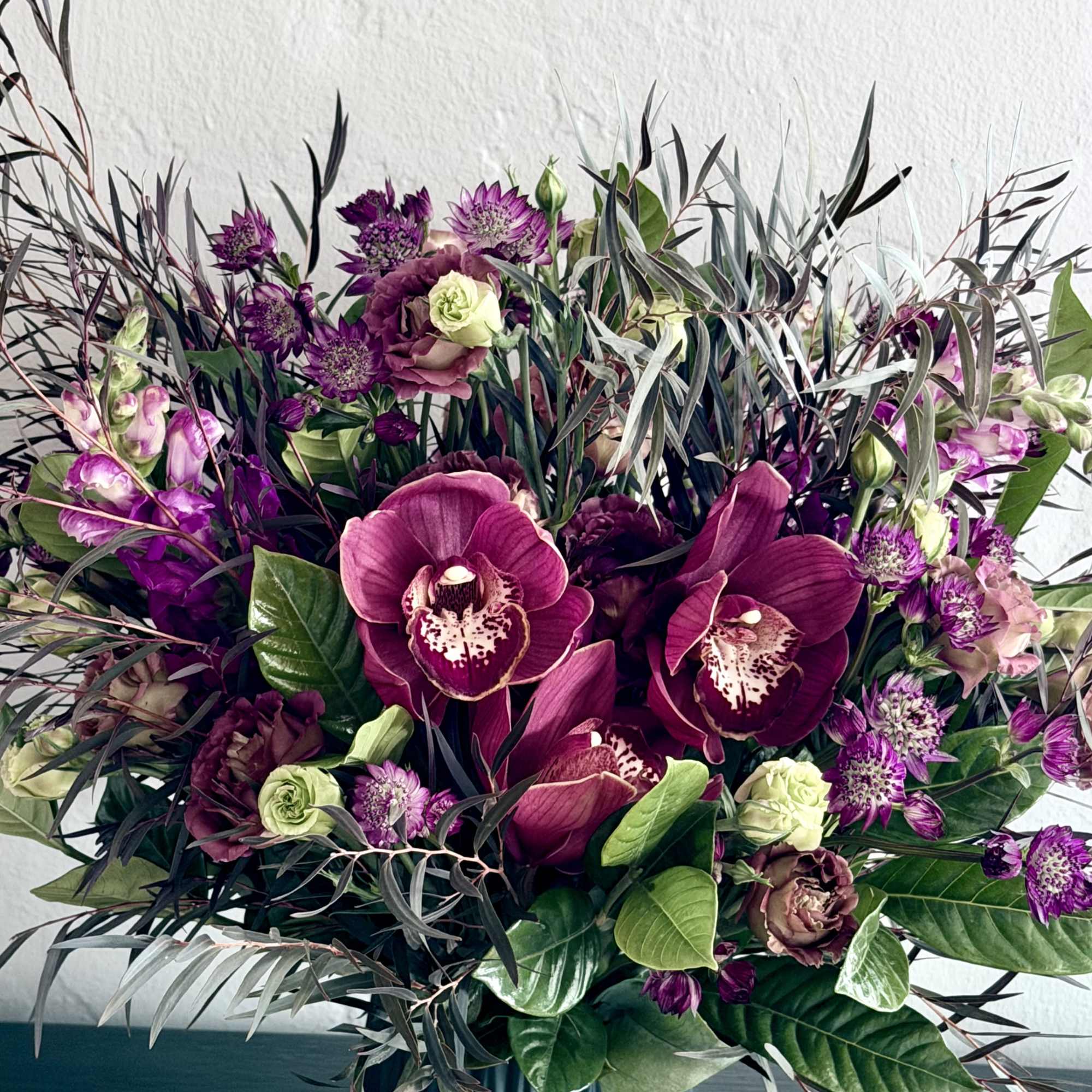 Unique and dramatic arrangement features richly colored maroon blooms! 