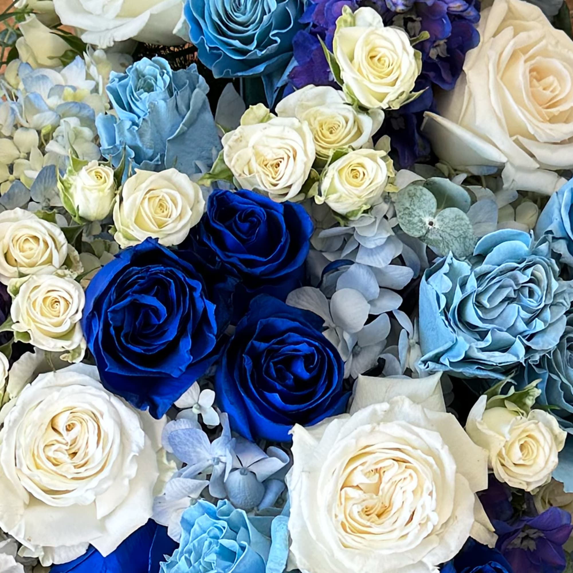 Blue flowers, light blue flowers, white flowers, and greenery. The standing cross