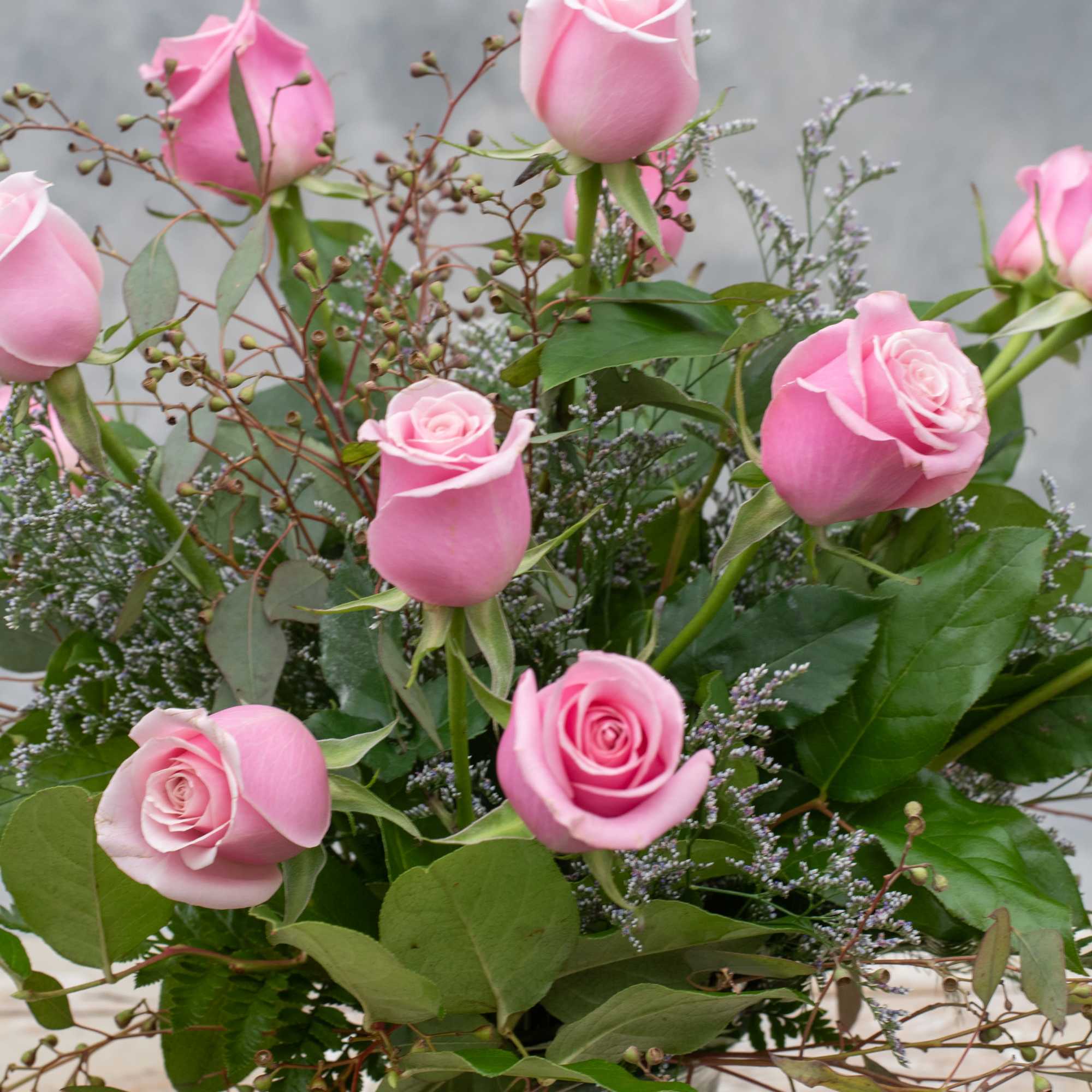 One dozen long stemmed pink roses classically arranged in a tall, tapered
