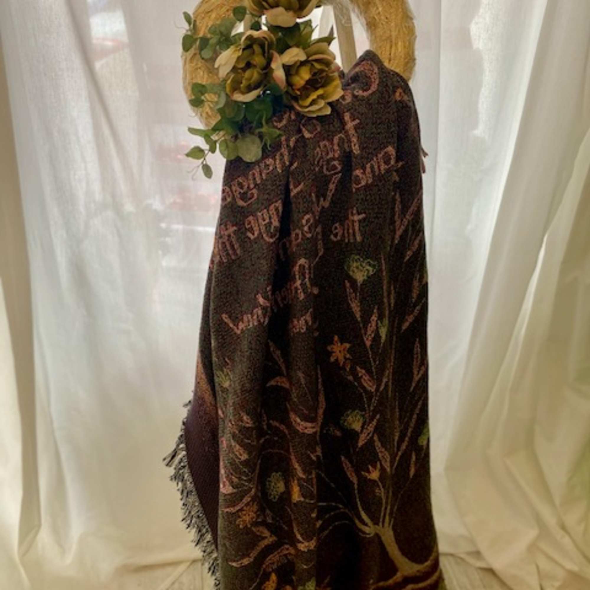 The "Walk Beside Us" throw displayed on a stand with silk flowers.