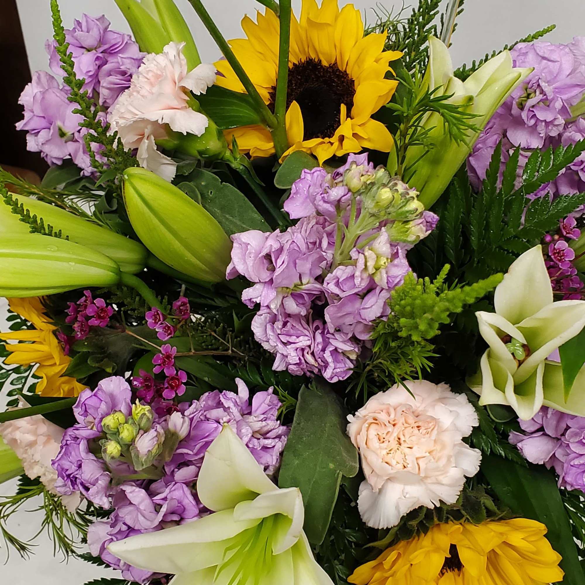 Fish bowl vase with white lily, sunflowers, pink carnations and lavender stock


