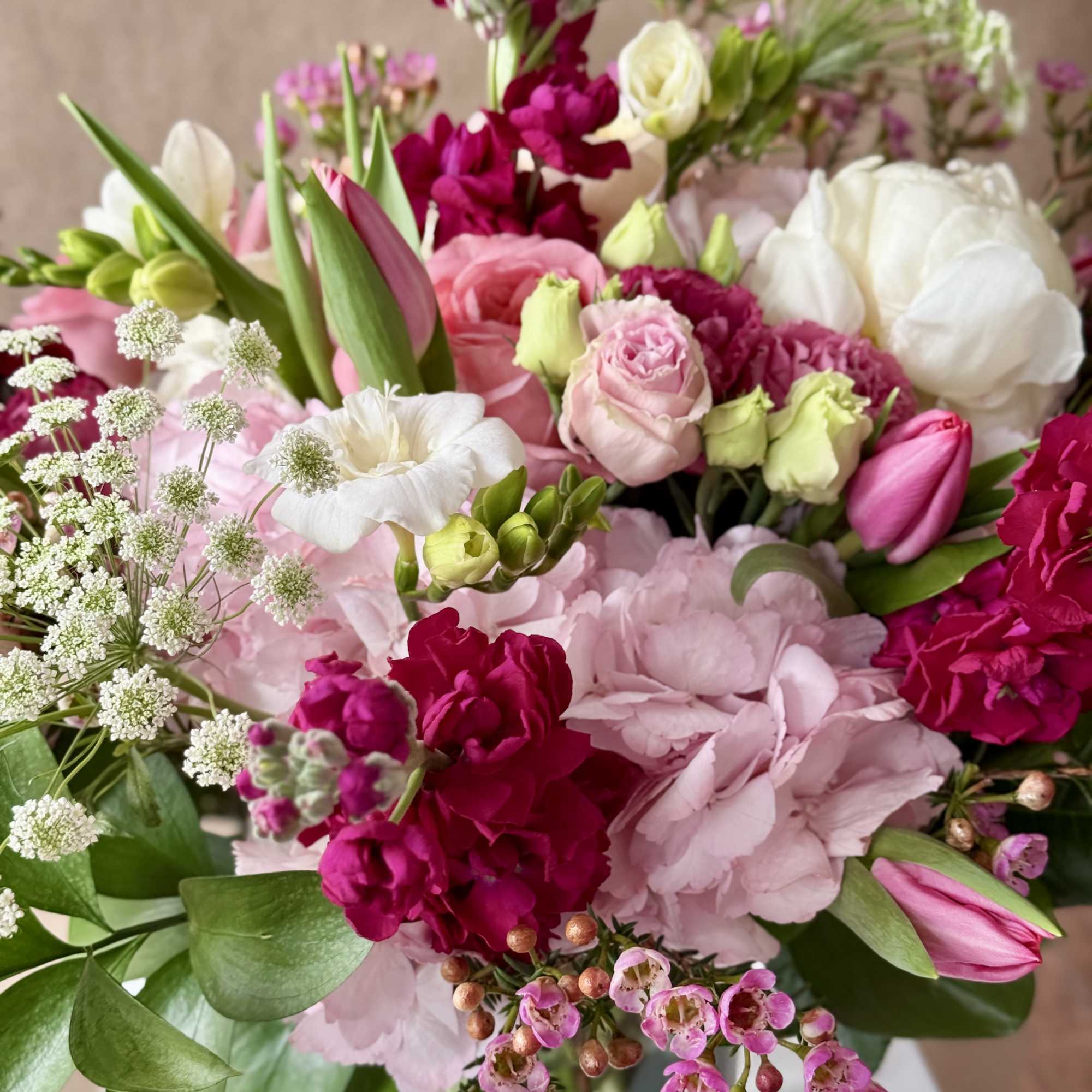 Romantic variety of fresh flowers arranged in a clear glass vase. 