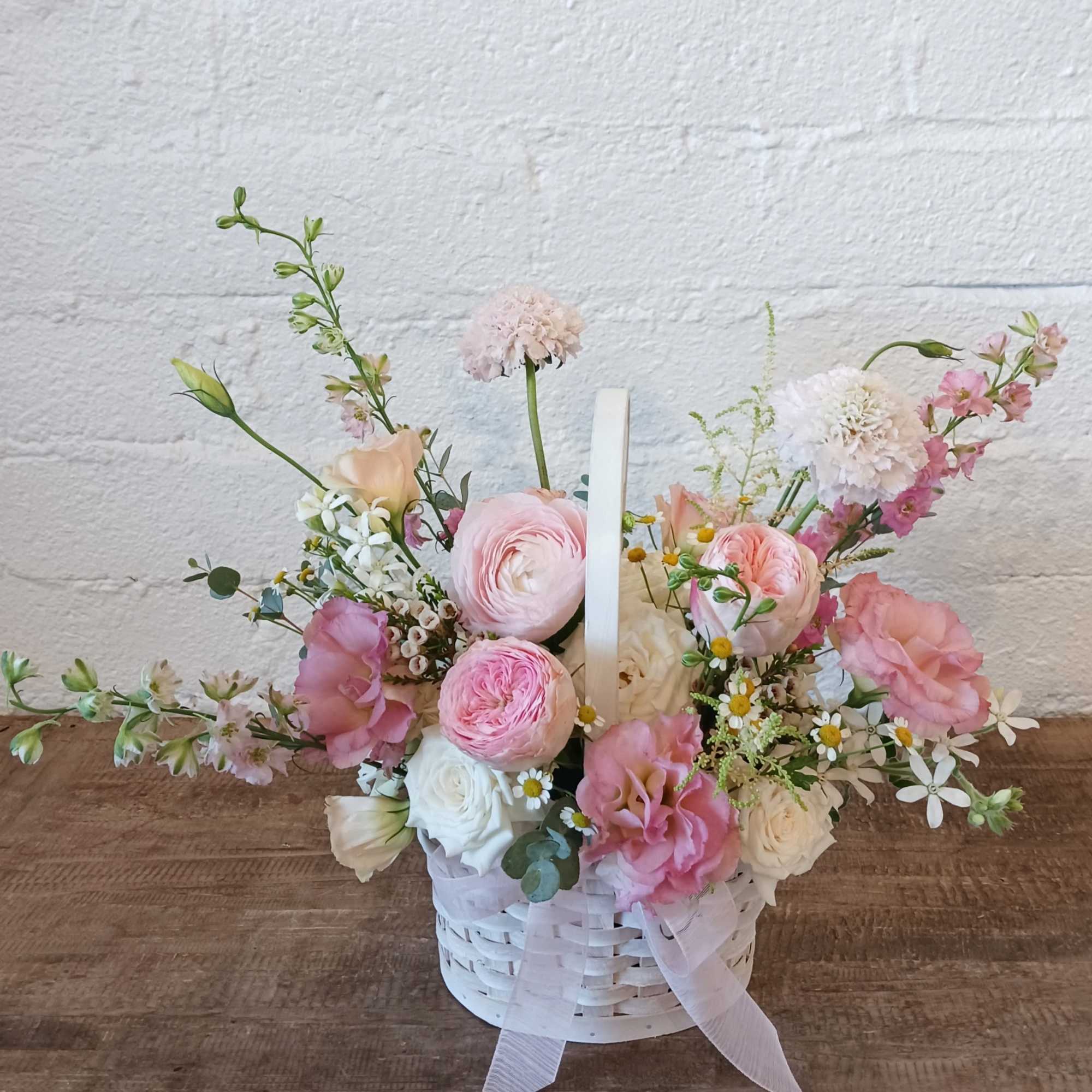 Designed in a basket, this arrangement overflows with soft shades of pink.