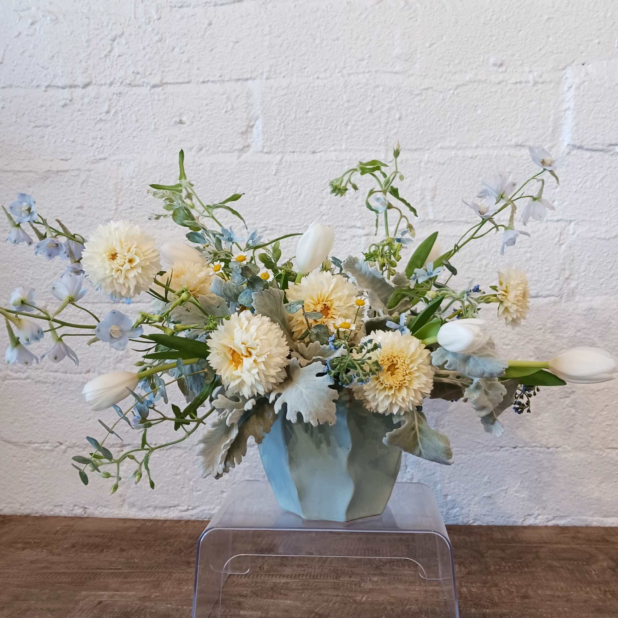 A beautiful arrangement full of dahlias and tulips arranged in a blue