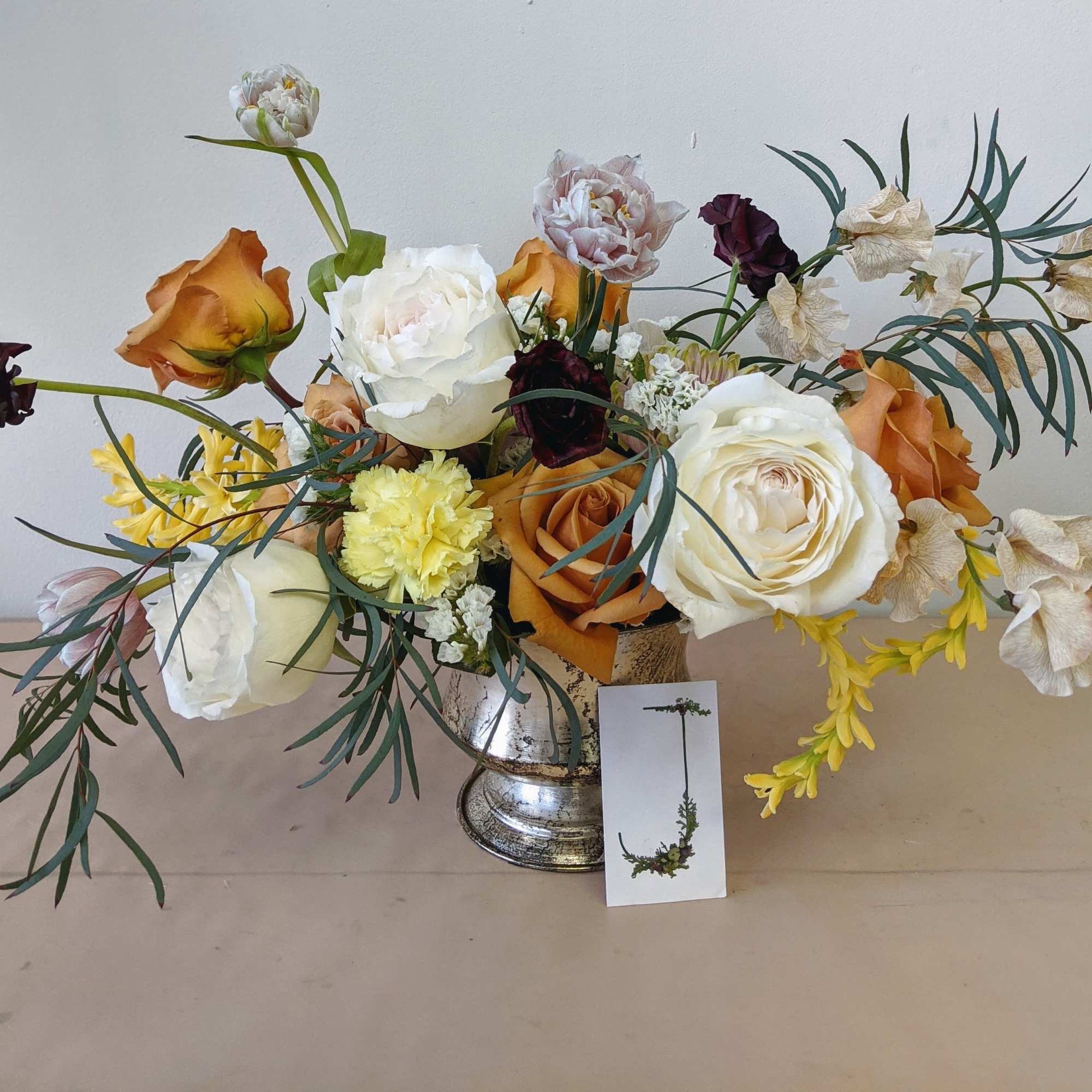 A neutral toned arrangement in a brassy compote.