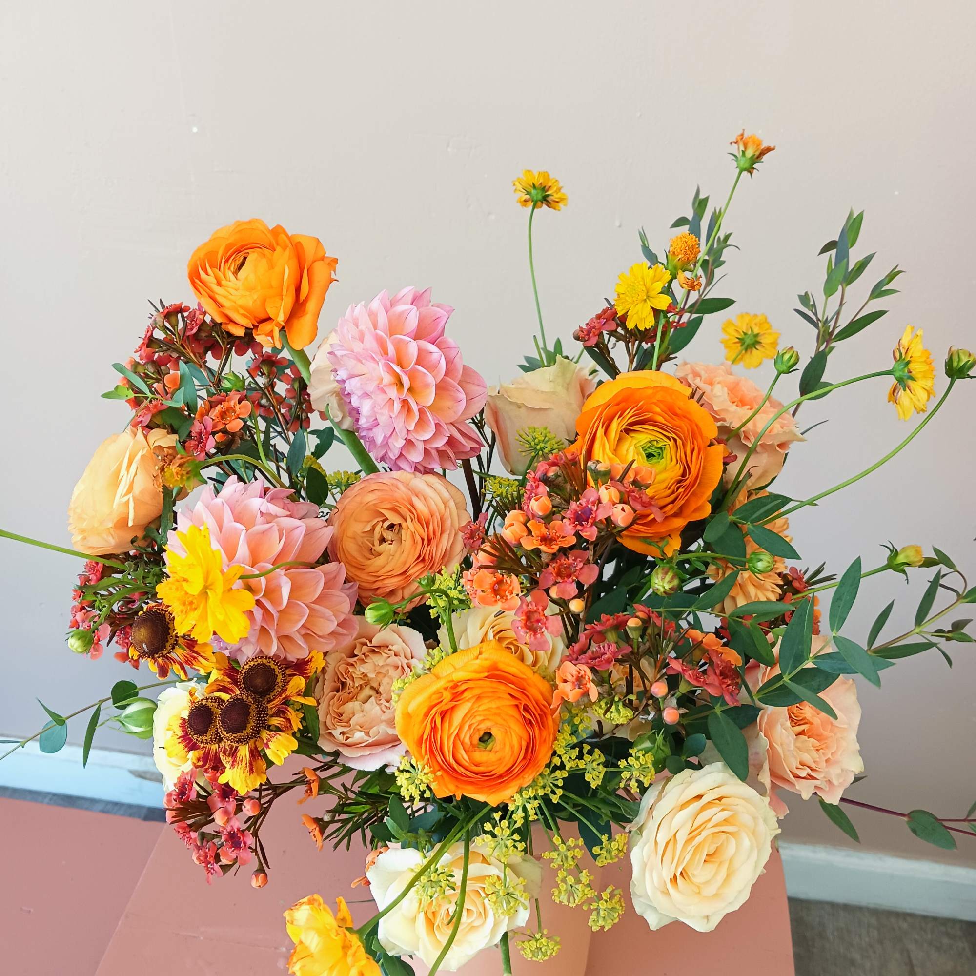 An orange dominant arrangement in a orange ceramic vase that will make