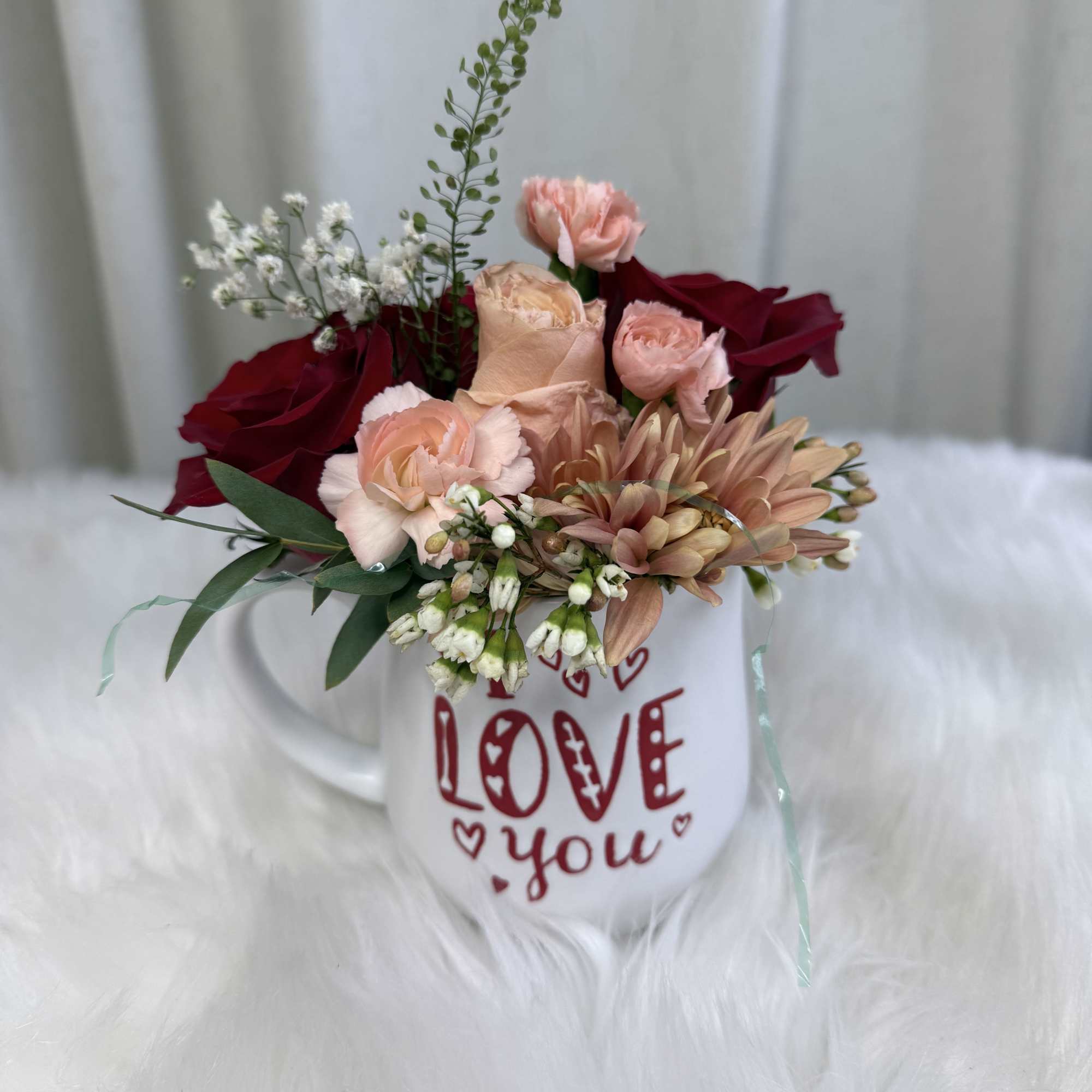 A beautiful "I love you" ceramic mug filled with fresh, seasonal flowers