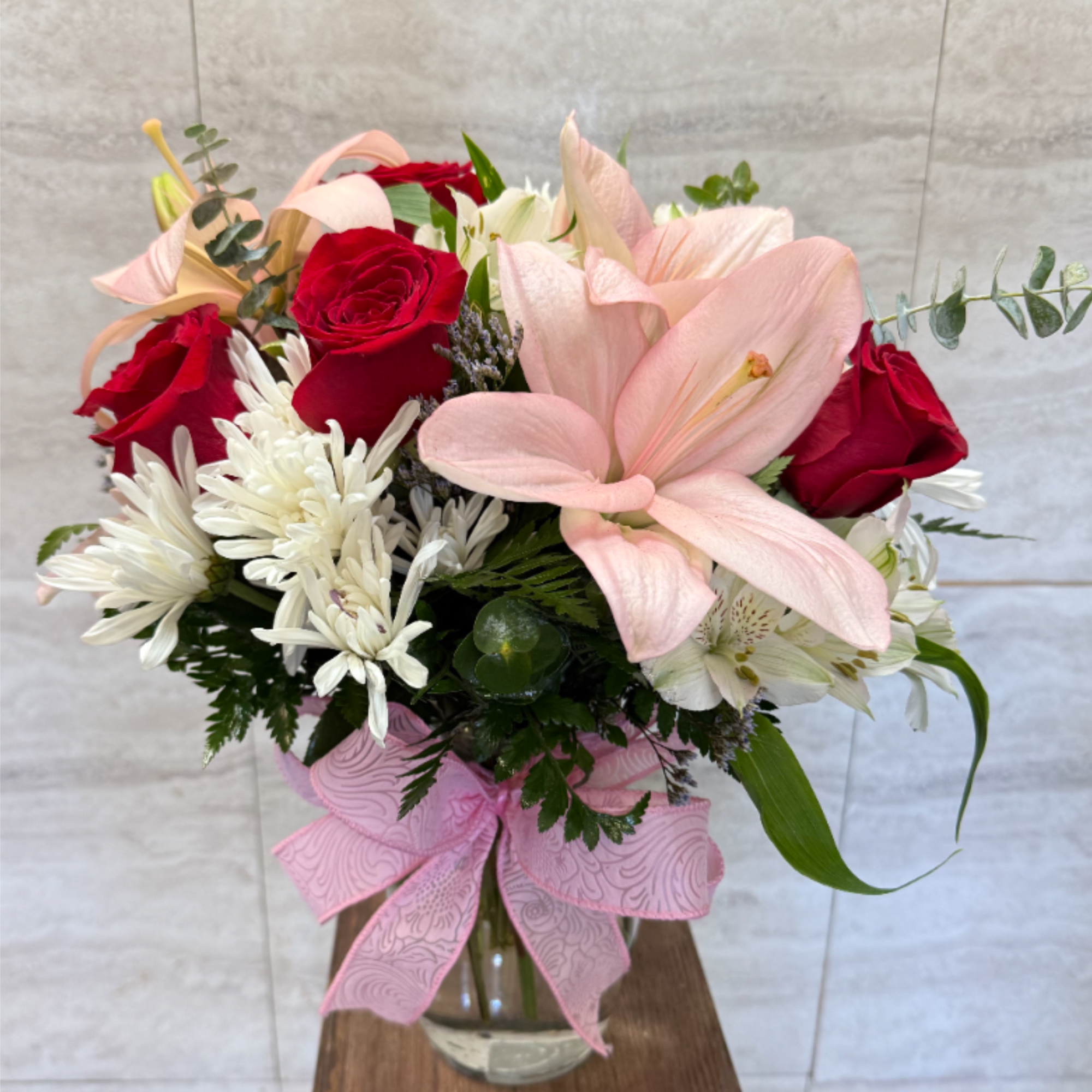This is a graceful mixed bouquet arranged in a clear glass vase.