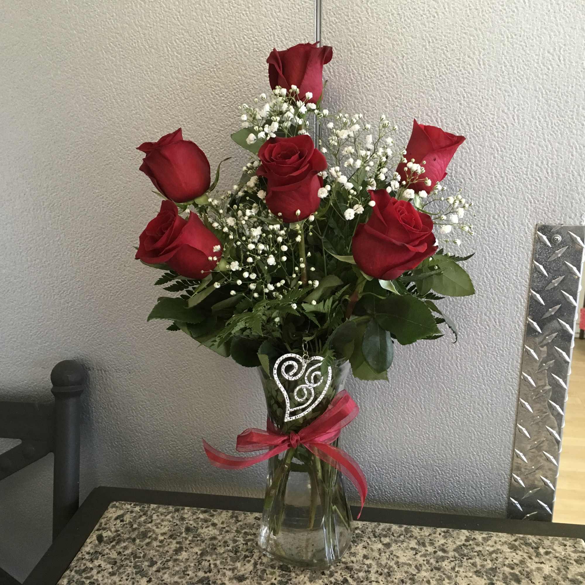 6 red roses arranged in glass vase w/ lg. silver heart pull