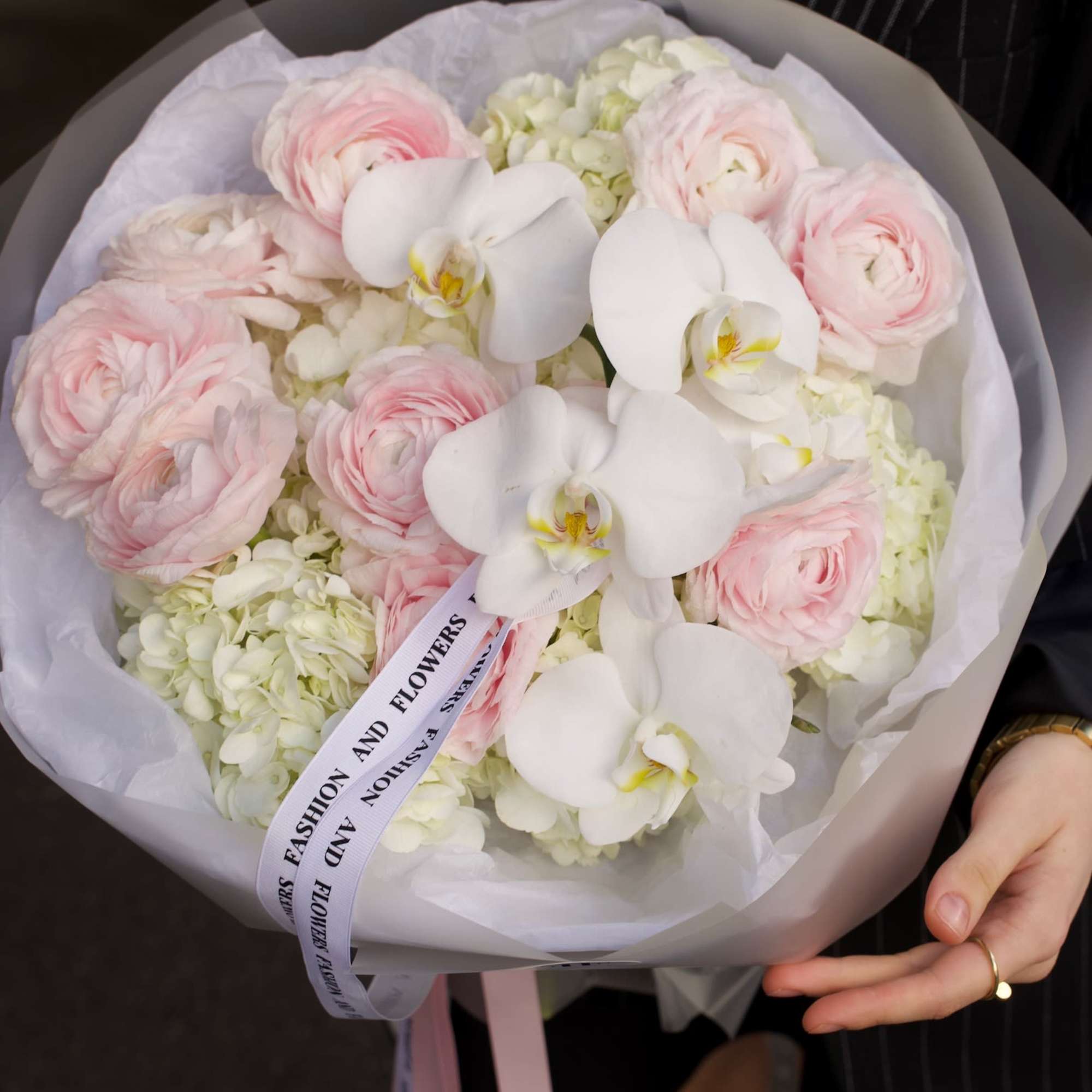 An airy couture-style bouquet featuring blush ranunculus, white phalaenopsis orchids, and soft