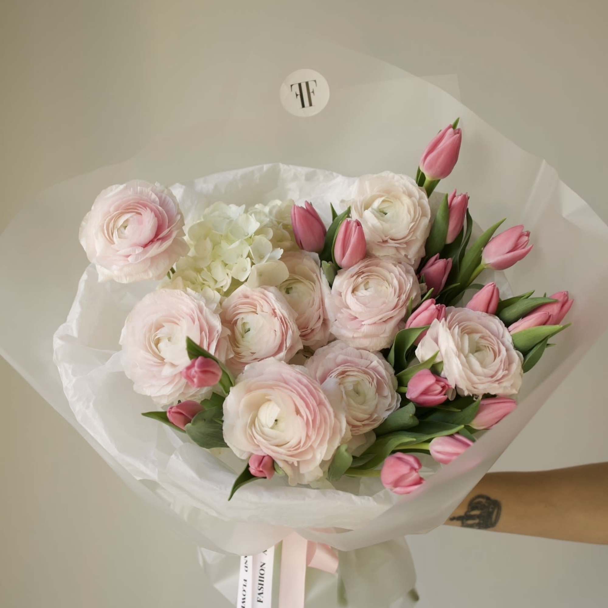 A delicate composition of blush ranunculus and soft pink tulips, designed to
