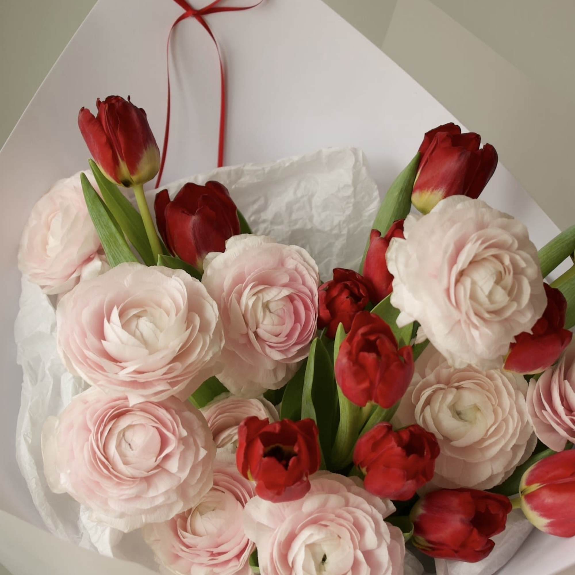 An elegant and romantic bouquet combining soft blush ranunculus with vibrant red